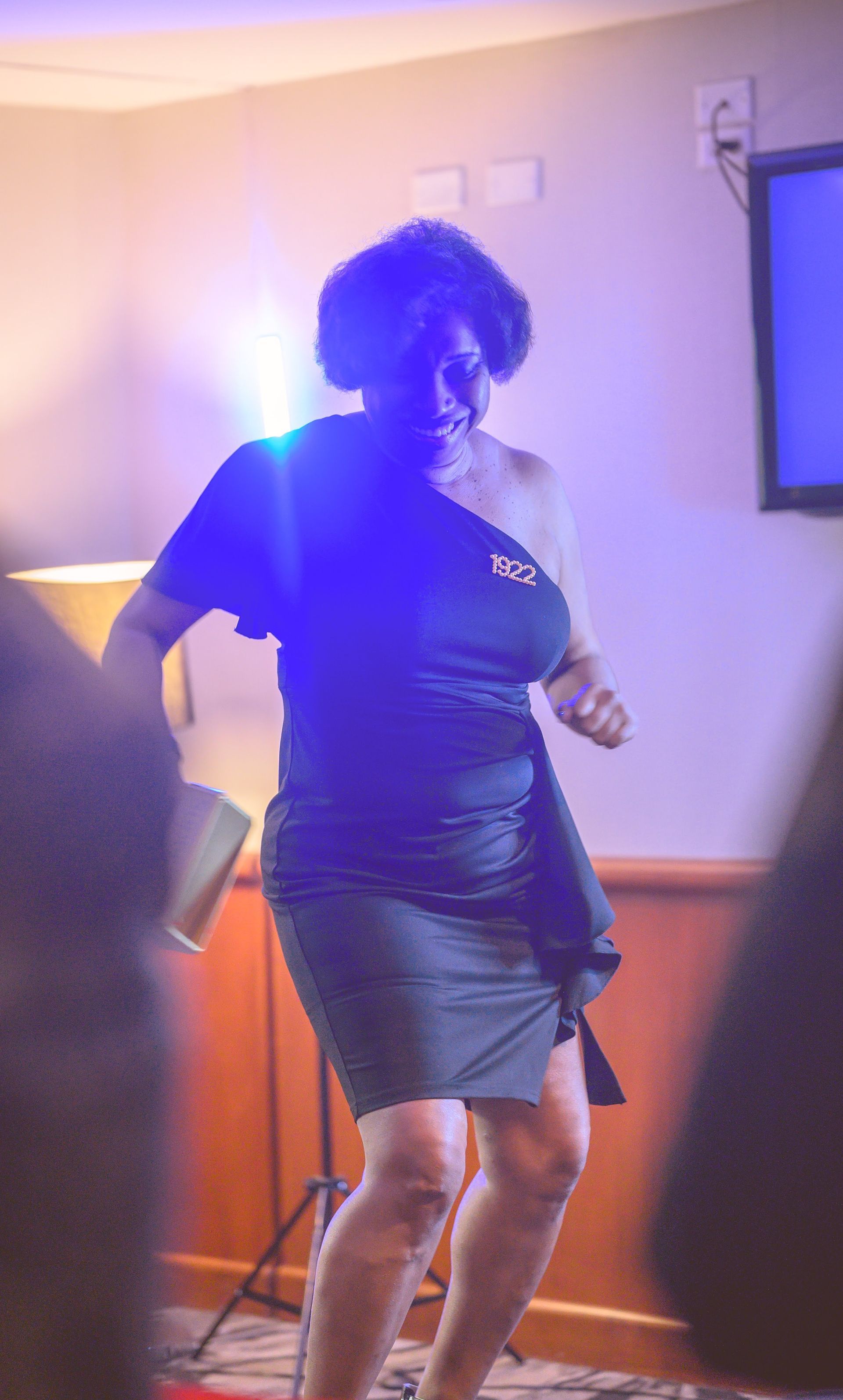 A woman in a green dress is dancing in a room.