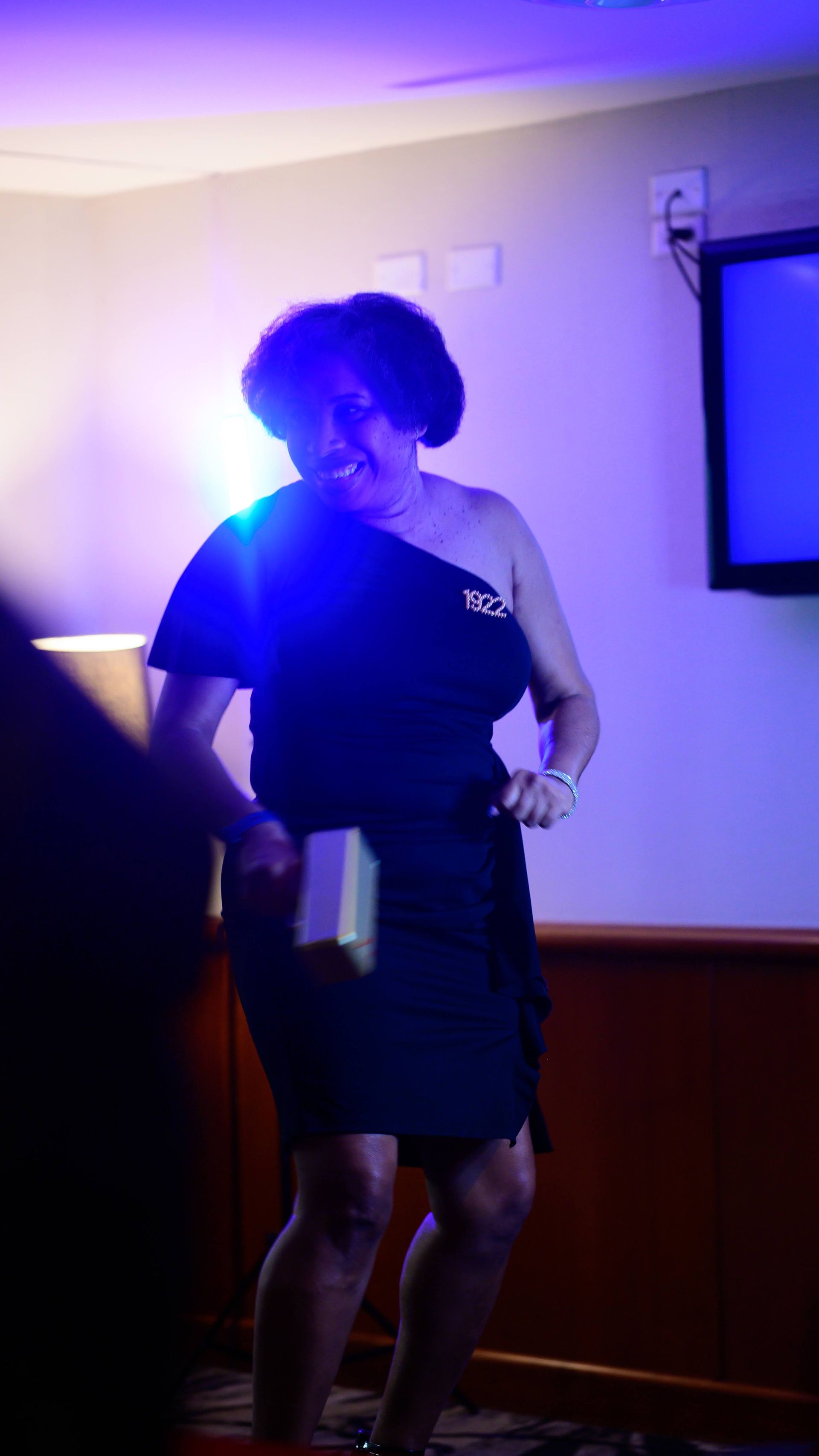 A woman in a black dress is dancing in a dark room.