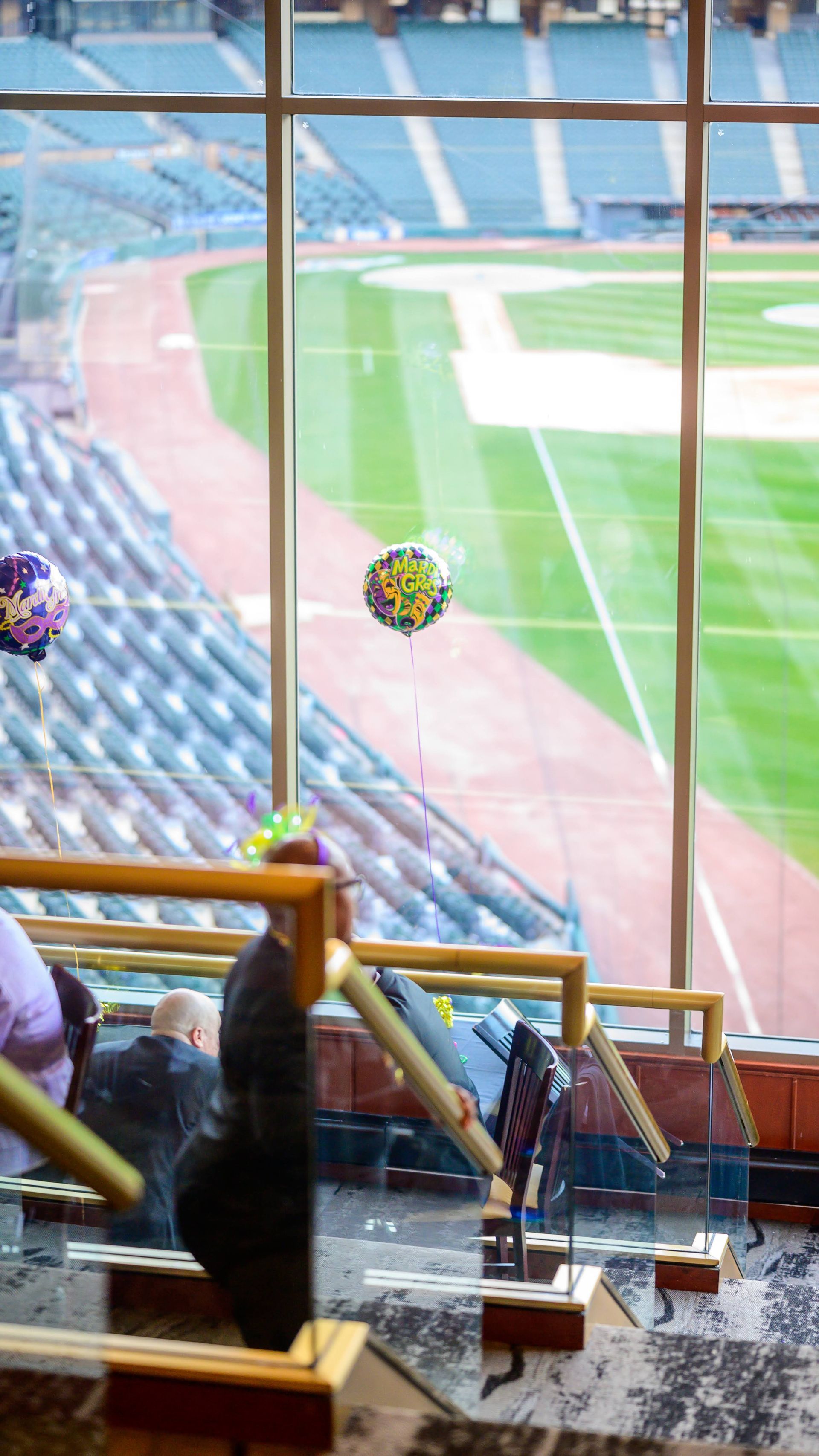 A group of people are sitting in a stadium looking out a window at a baseball field.