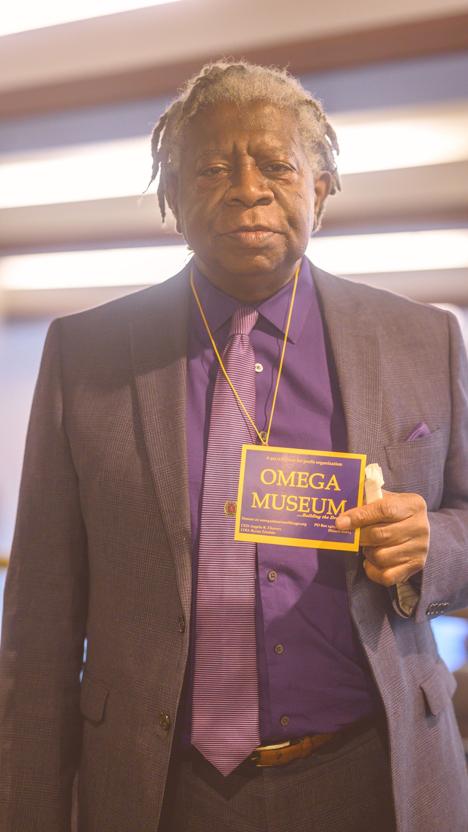 A man in a suit and tie is holding a name tag.