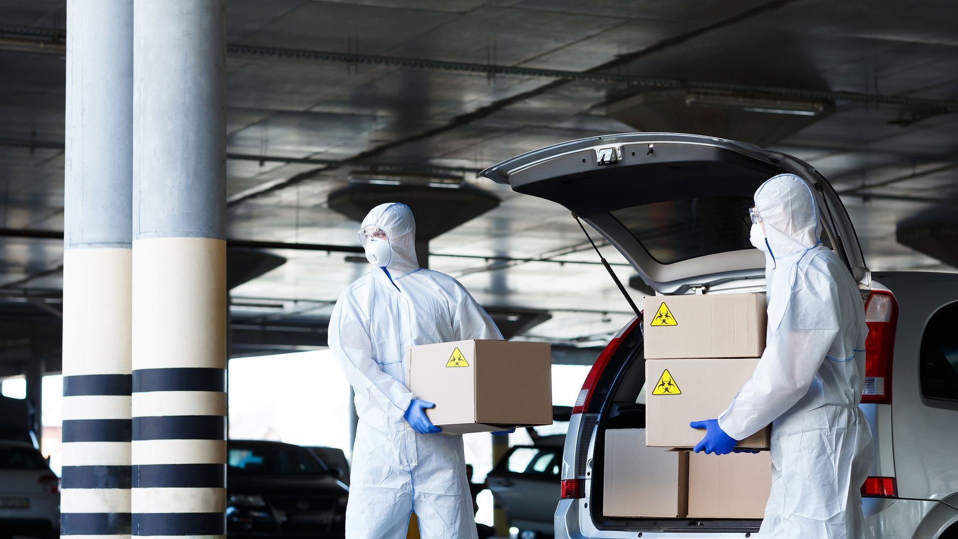 Dos hombres con trajes de protección están cargando cajas en la parte trasera de un automóvil. Carga IMO
M3GA LOGISTICA