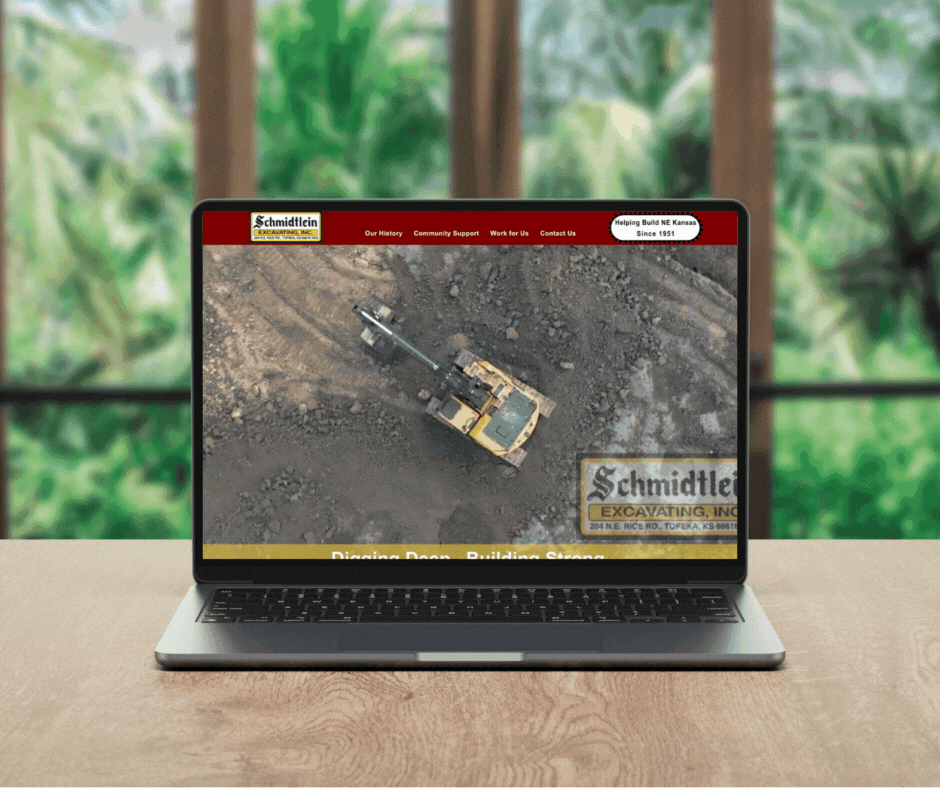 A laptop computer is sitting on a desk next to a vase of dried flowers.