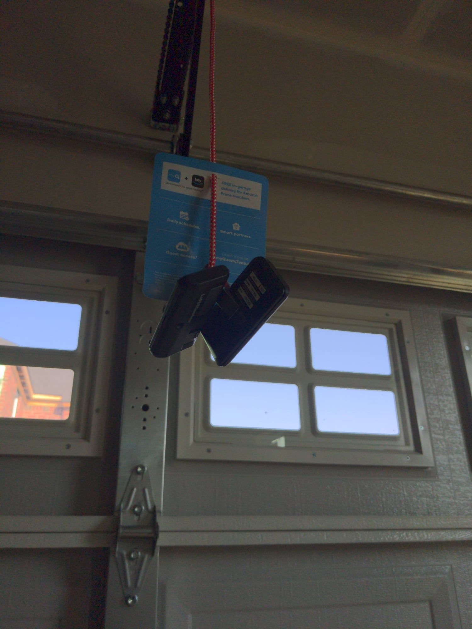 Black shoes hanging by their laces from a blue sign inside a garage with small windows.