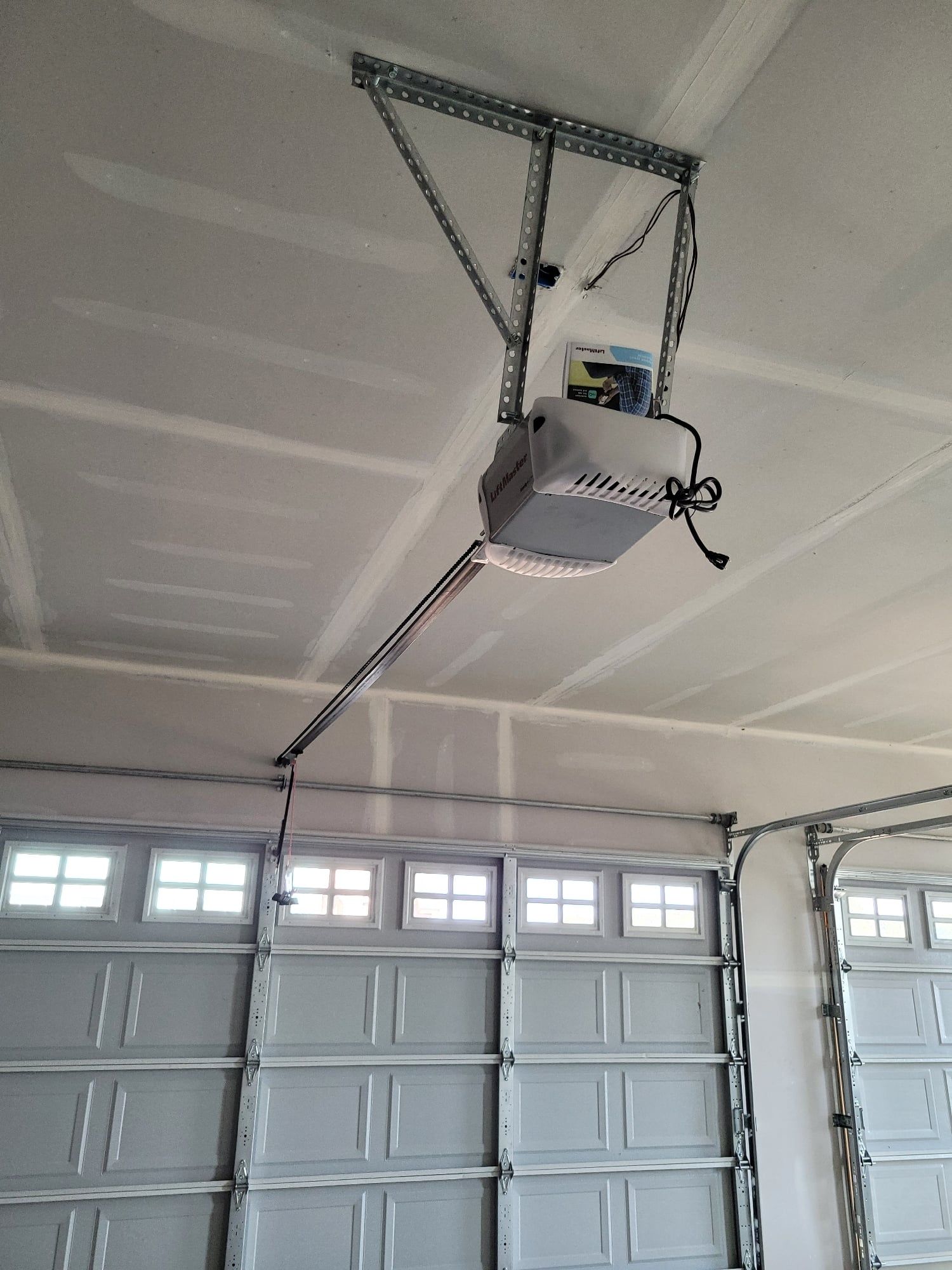 Garage door opener mounted on a ceiling above a row of closed garage doors