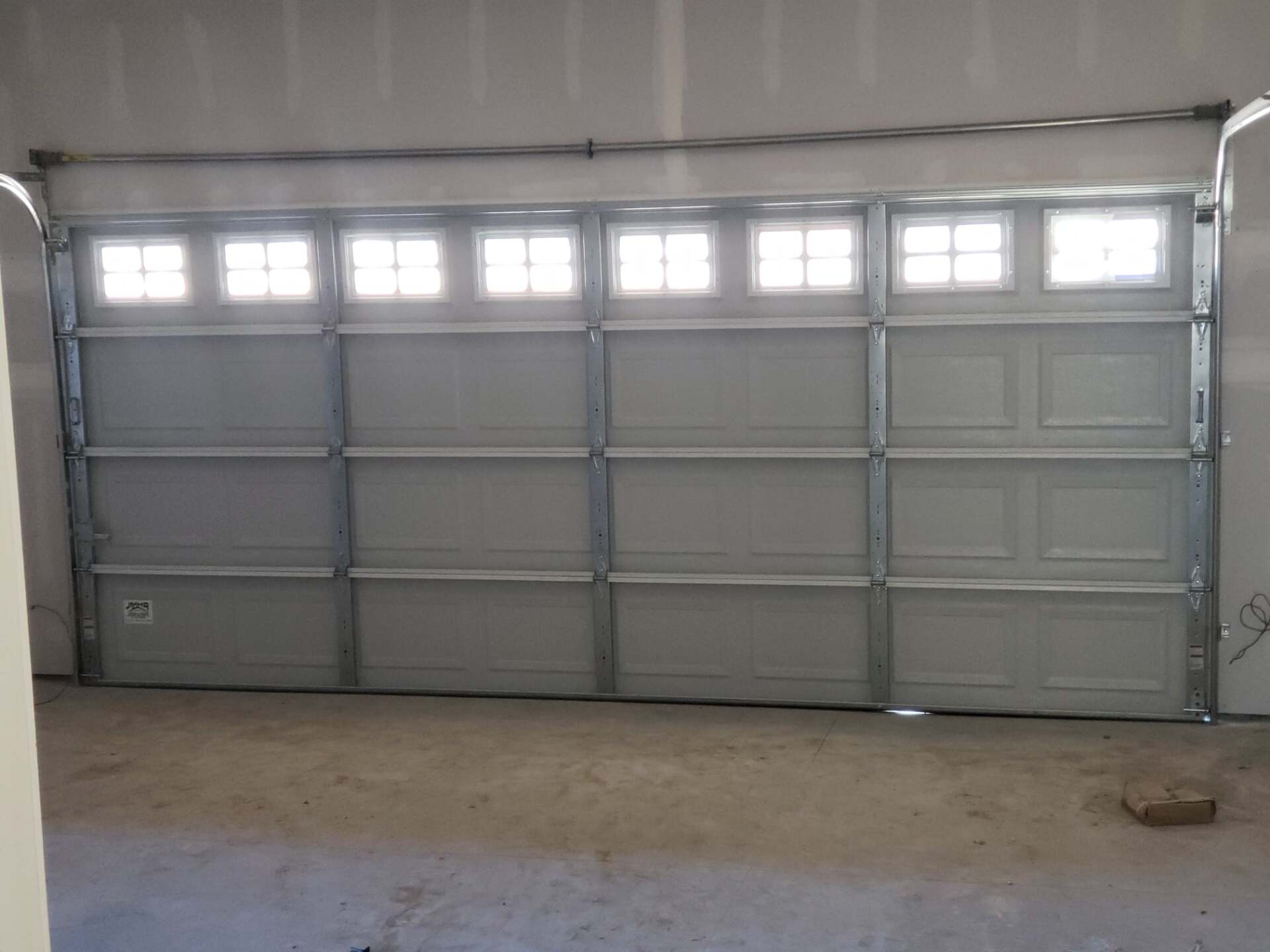 Closed gray garage door in a bare, unfinished garage interior