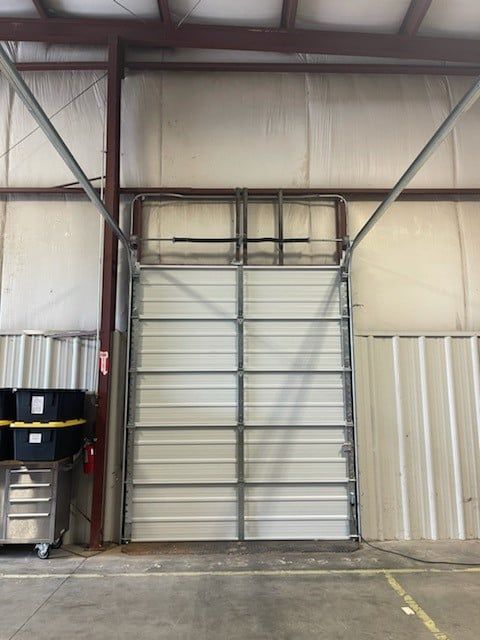 Industrial warehouse interior with a metal roll-up door centered in a high-ceilinged storage space