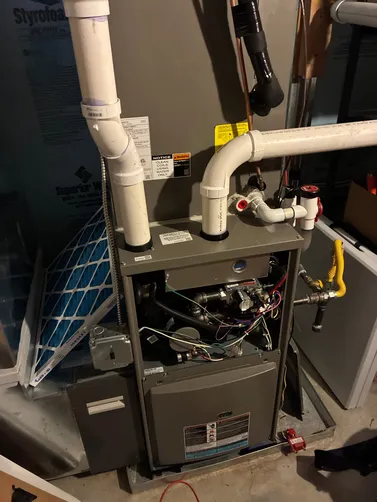 Furnace with open door, showing internal components and white PVC pipes.