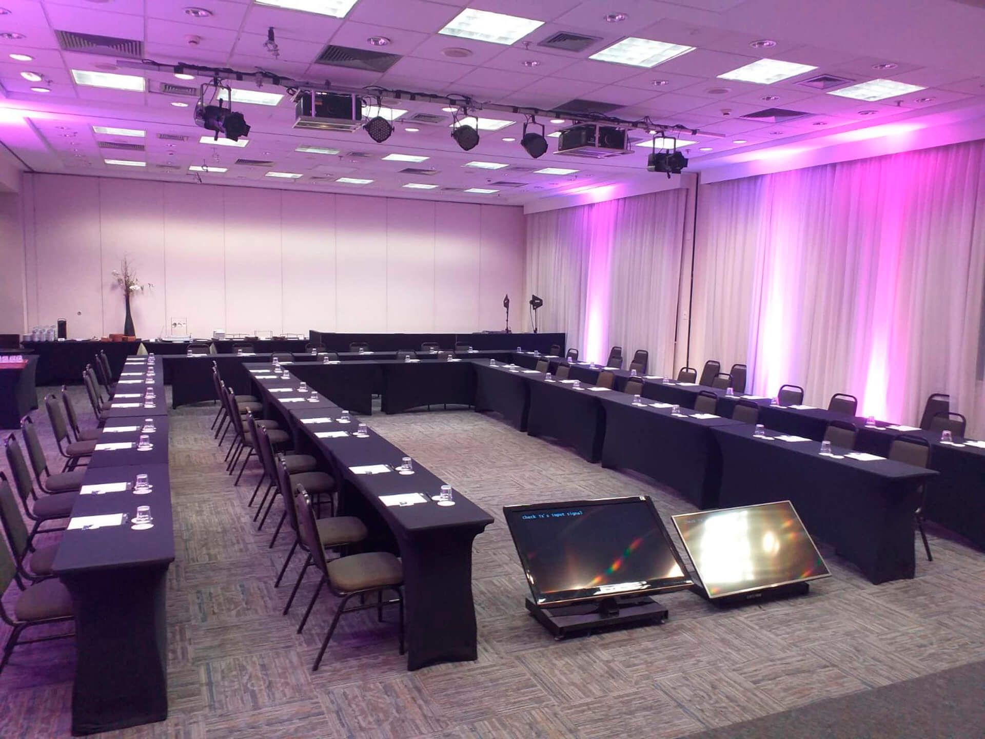 Uma grande sala de conferências com mesas e cadeiras preparadas para uma reunião.