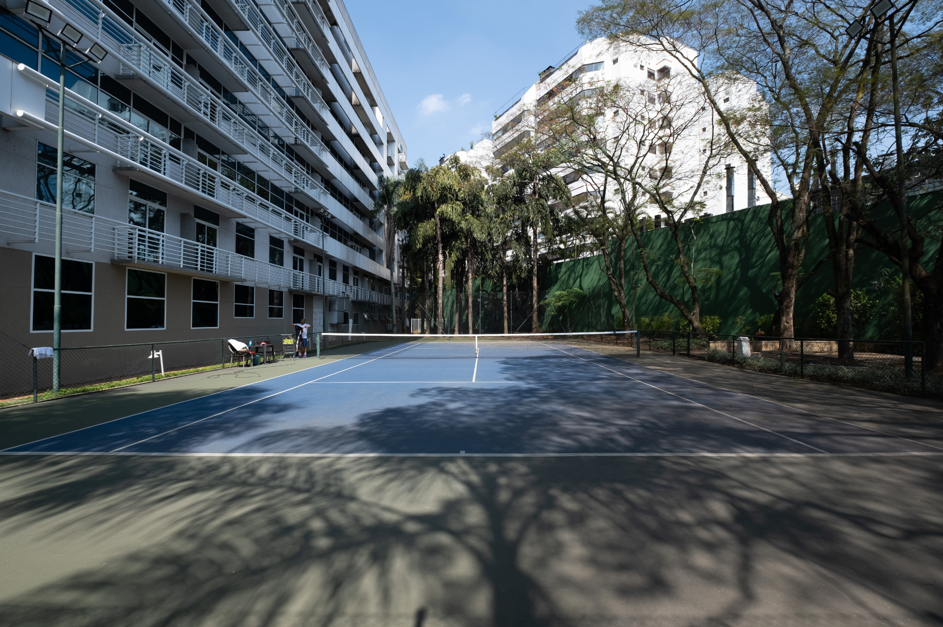 Uma quadra de tênis em frente a um prédio com uma montanha ao fundo