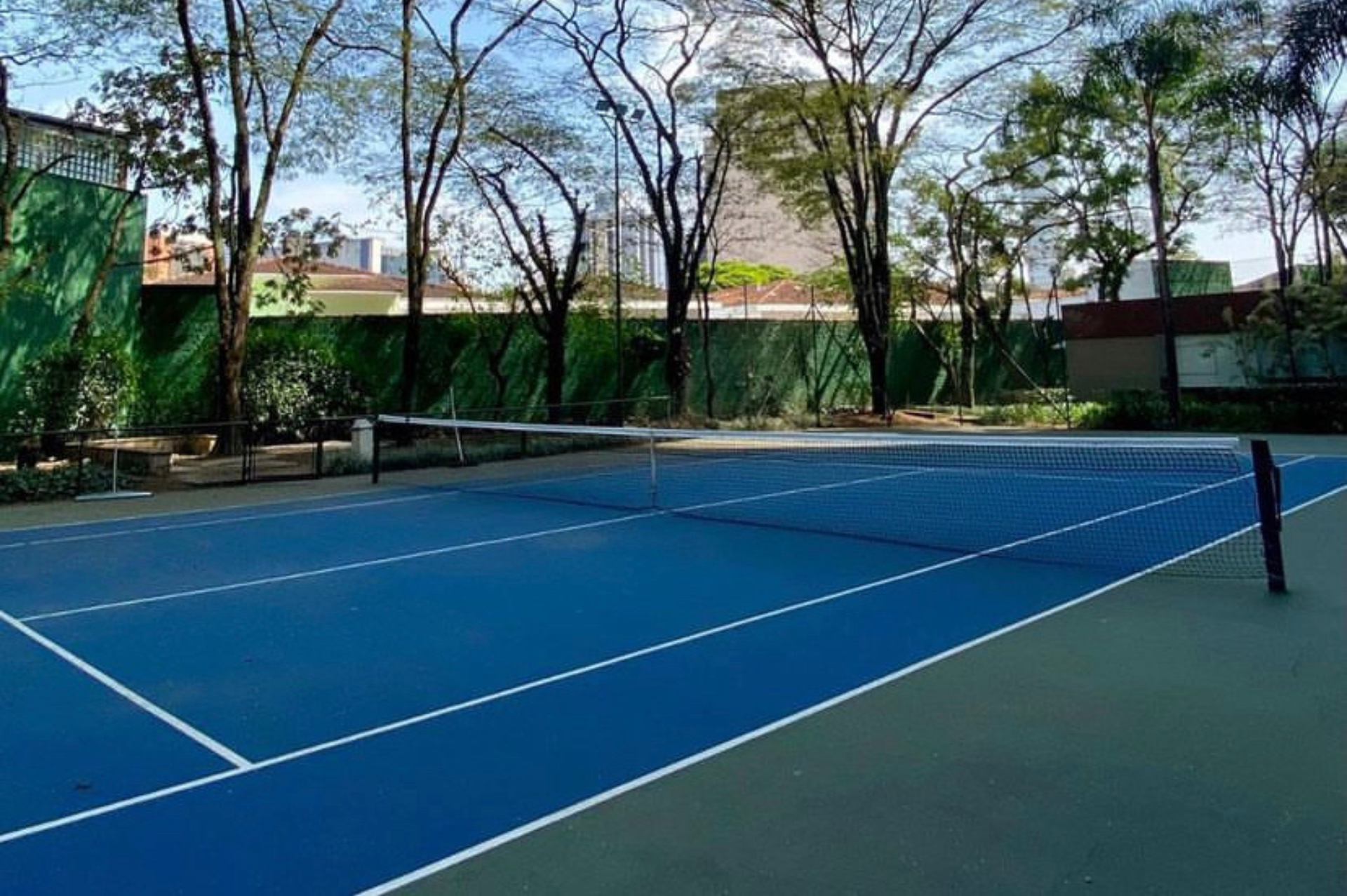 Uma quadra de tênis azul com árvores ao fundo.