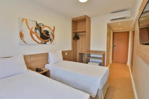 Um quarto de hotel com duas camas e uma televisão.
