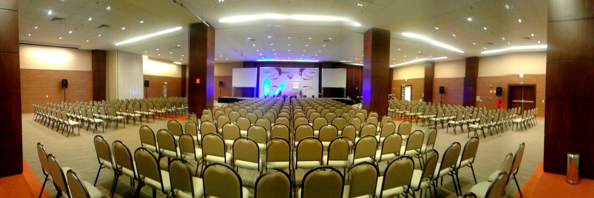 Uma grande sala de conferências com fileiras de cadeiras e um palco.