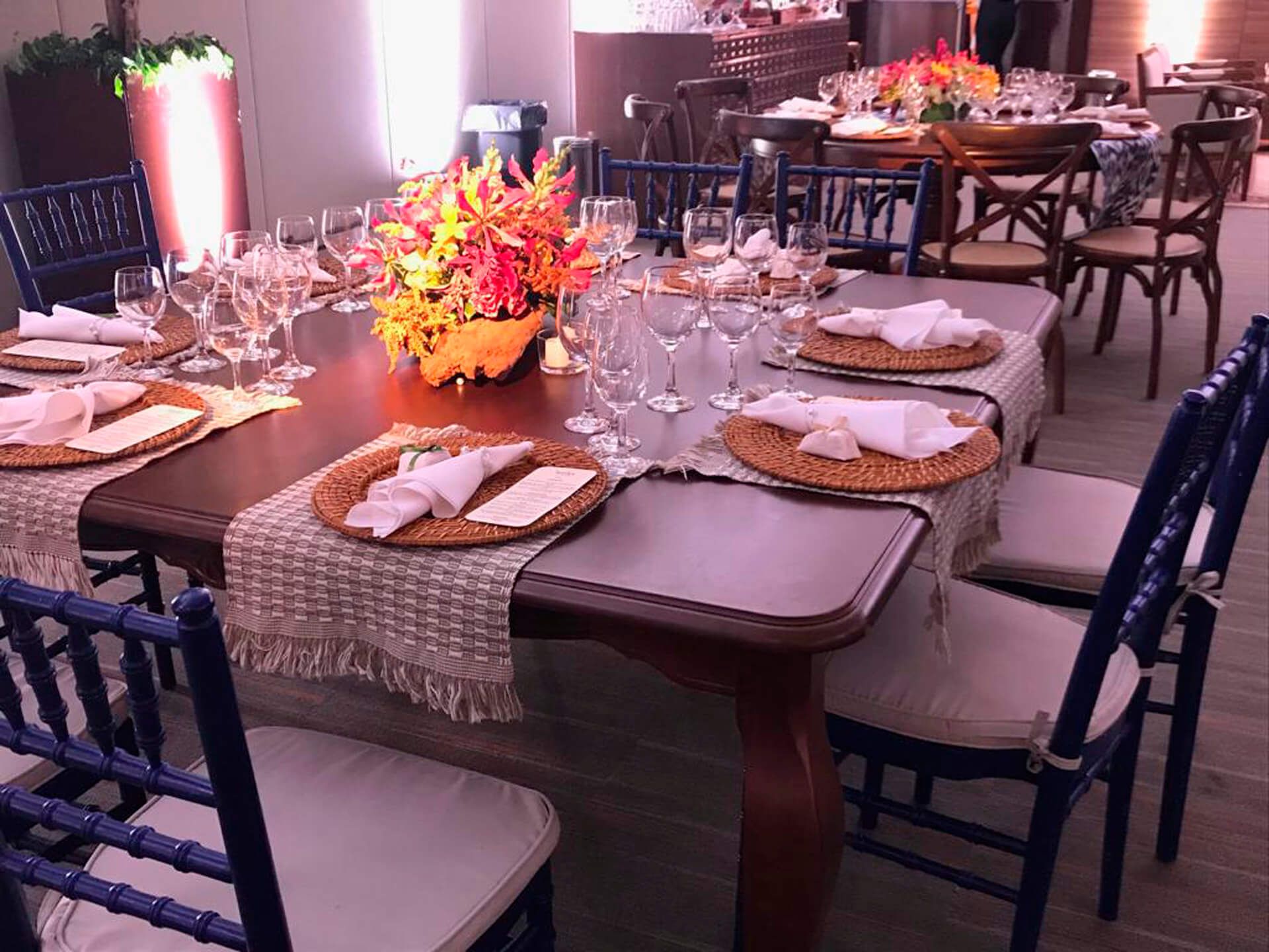 Uma mesa com pratos, guardanapos, copos e um vaso de flores.