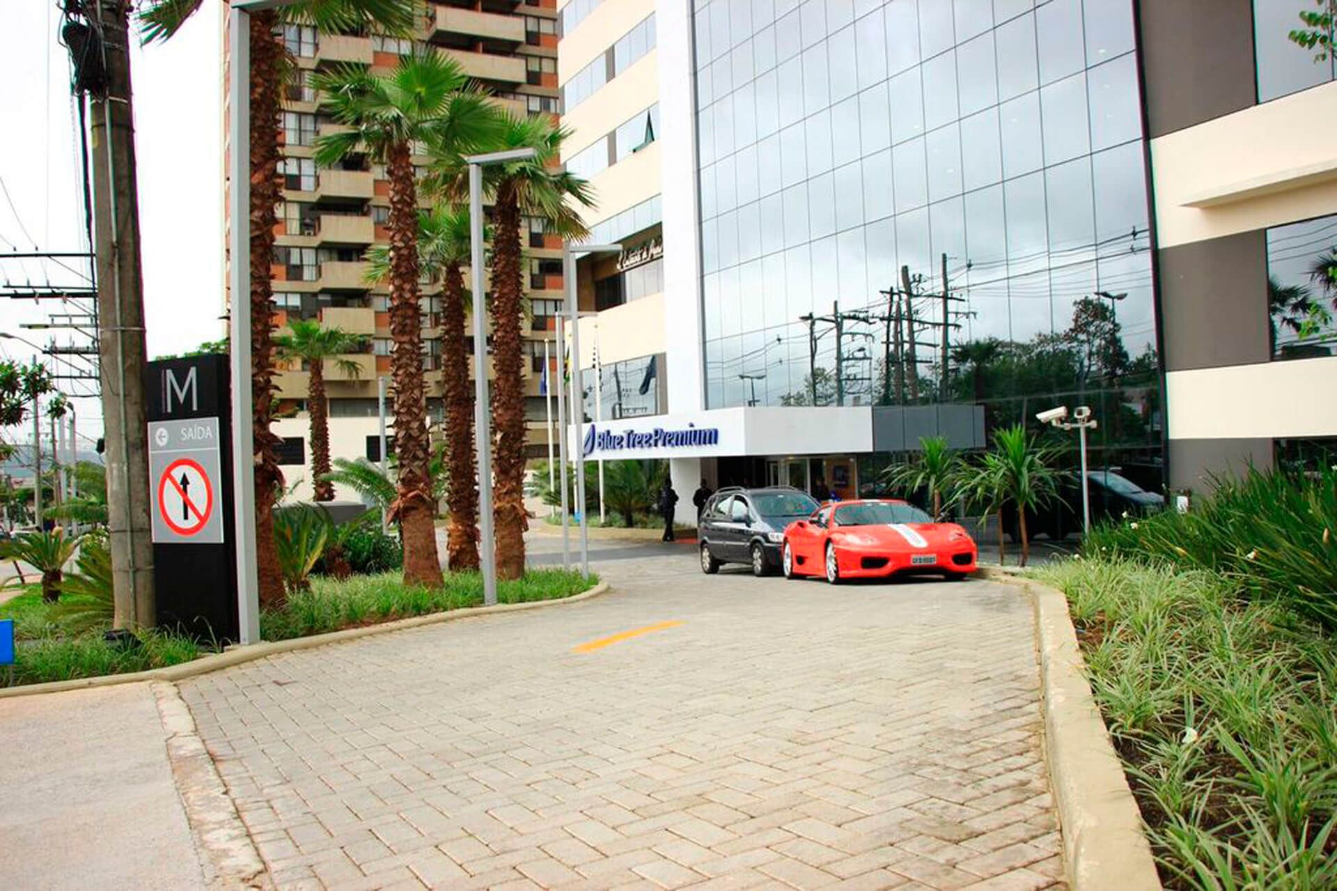 Um carro esportivo vermelho está estacionado em frente a um hotel