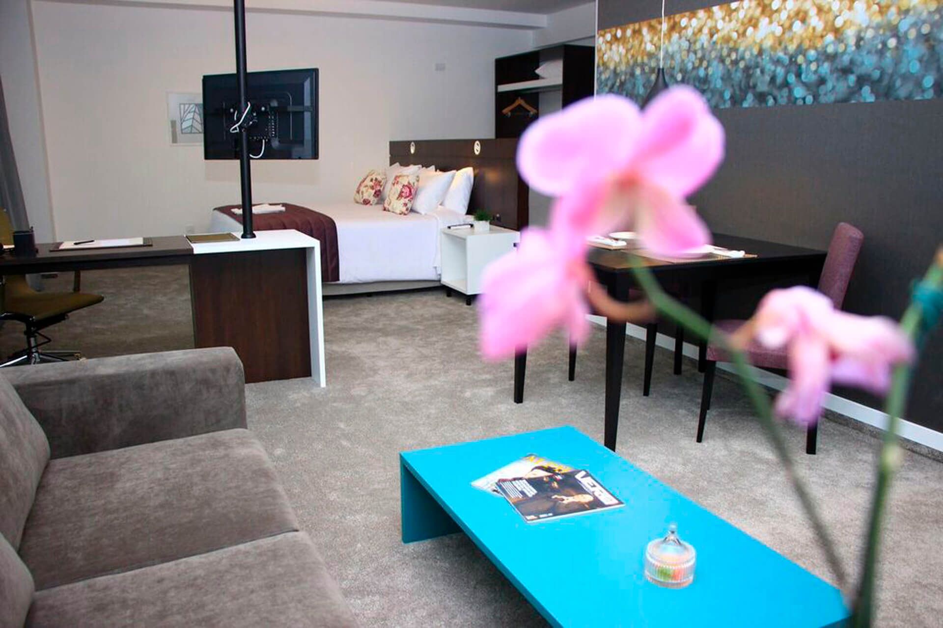 Uma sala de estar com uma mesa de centro azul e flores rosas