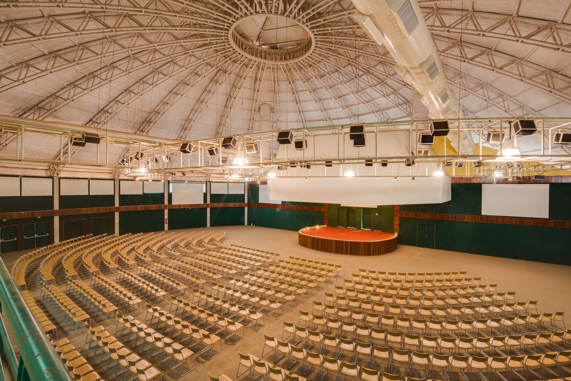 Um grande auditório com fileiras de cadeiras e um palco no meio