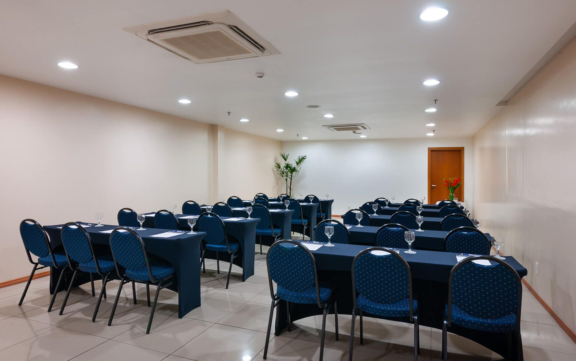 Uma sala de conferências com mesas e cadeiras preparadas para uma reunião