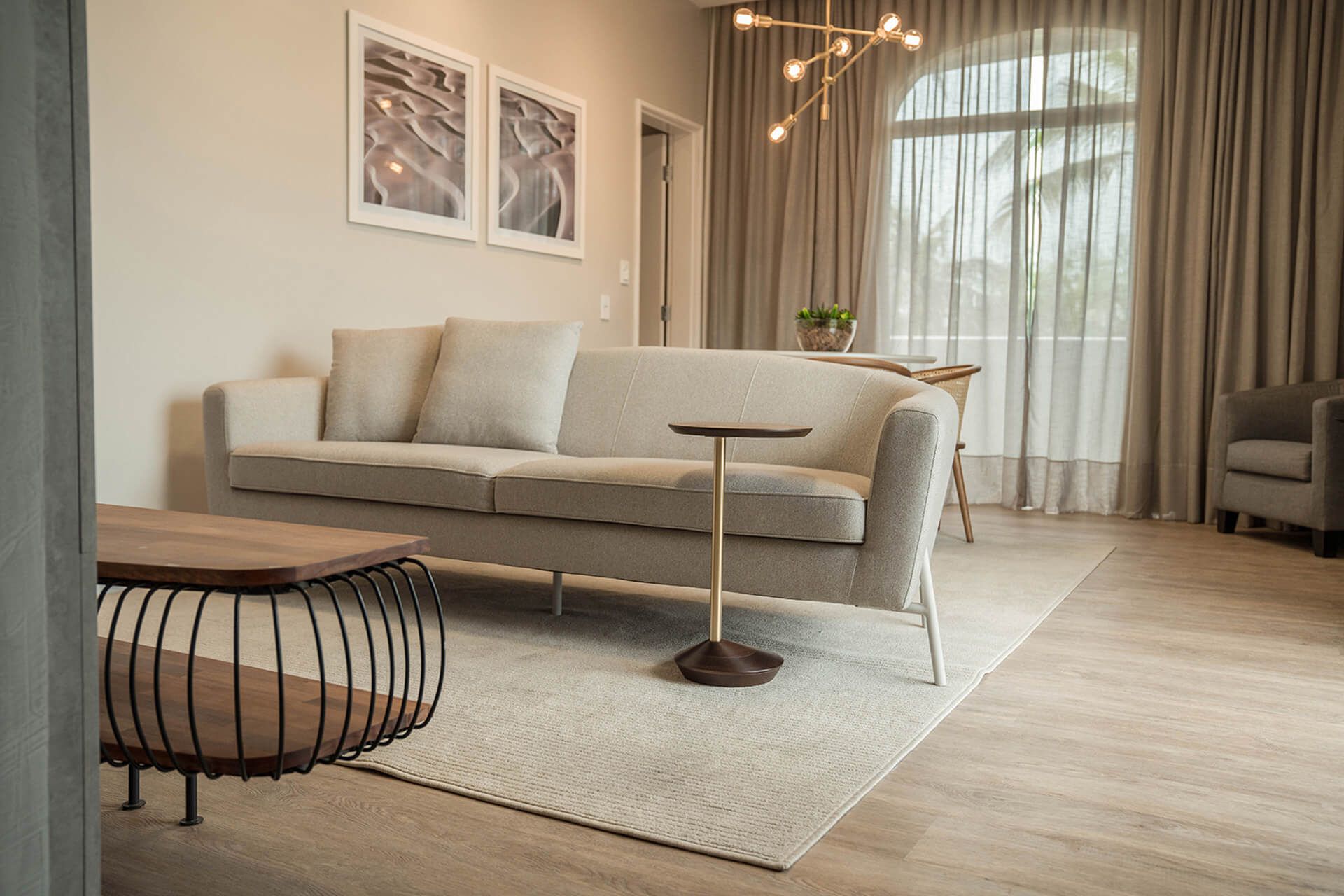 Uma sala de estar com sofá, mesa, cadeiras e cortinas.