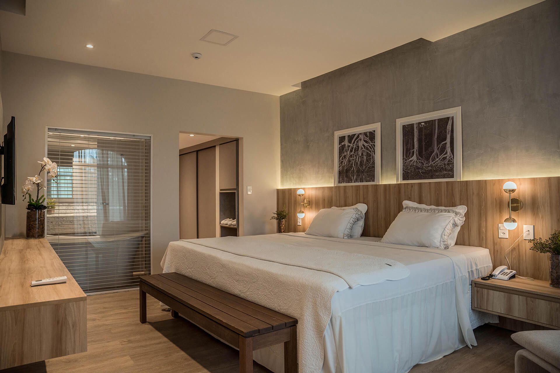 Um quarto de hotel com uma cama king size e um banco.