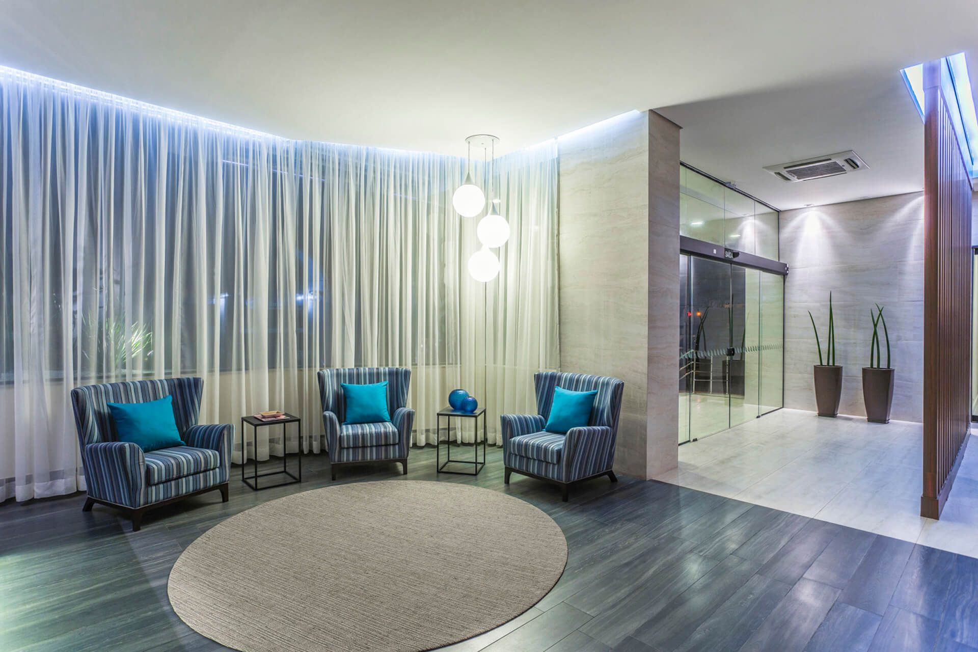 Um lobby com cadeiras, mesas e um tapete redondo.