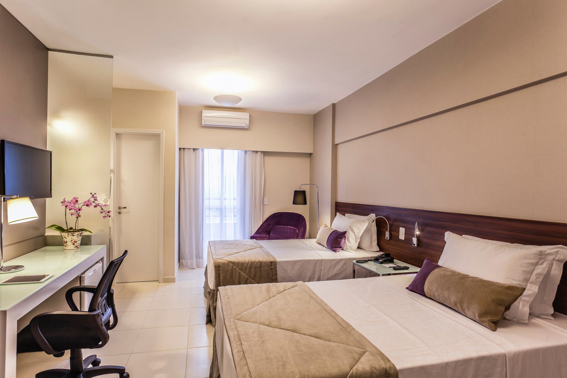 Um quarto de hotel com duas camas, uma escrivaninha e uma cadeira.