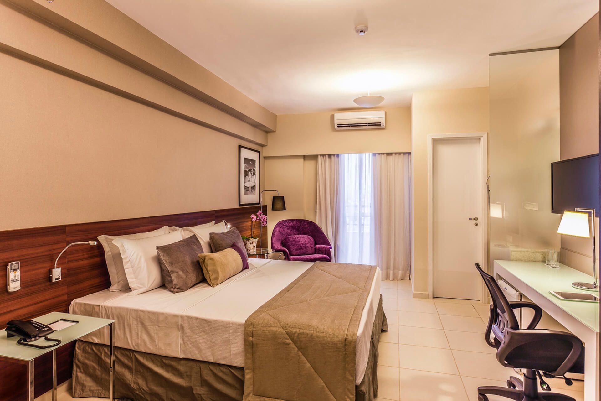 Um quarto de hotel com uma cama king size e uma escrivaninha.