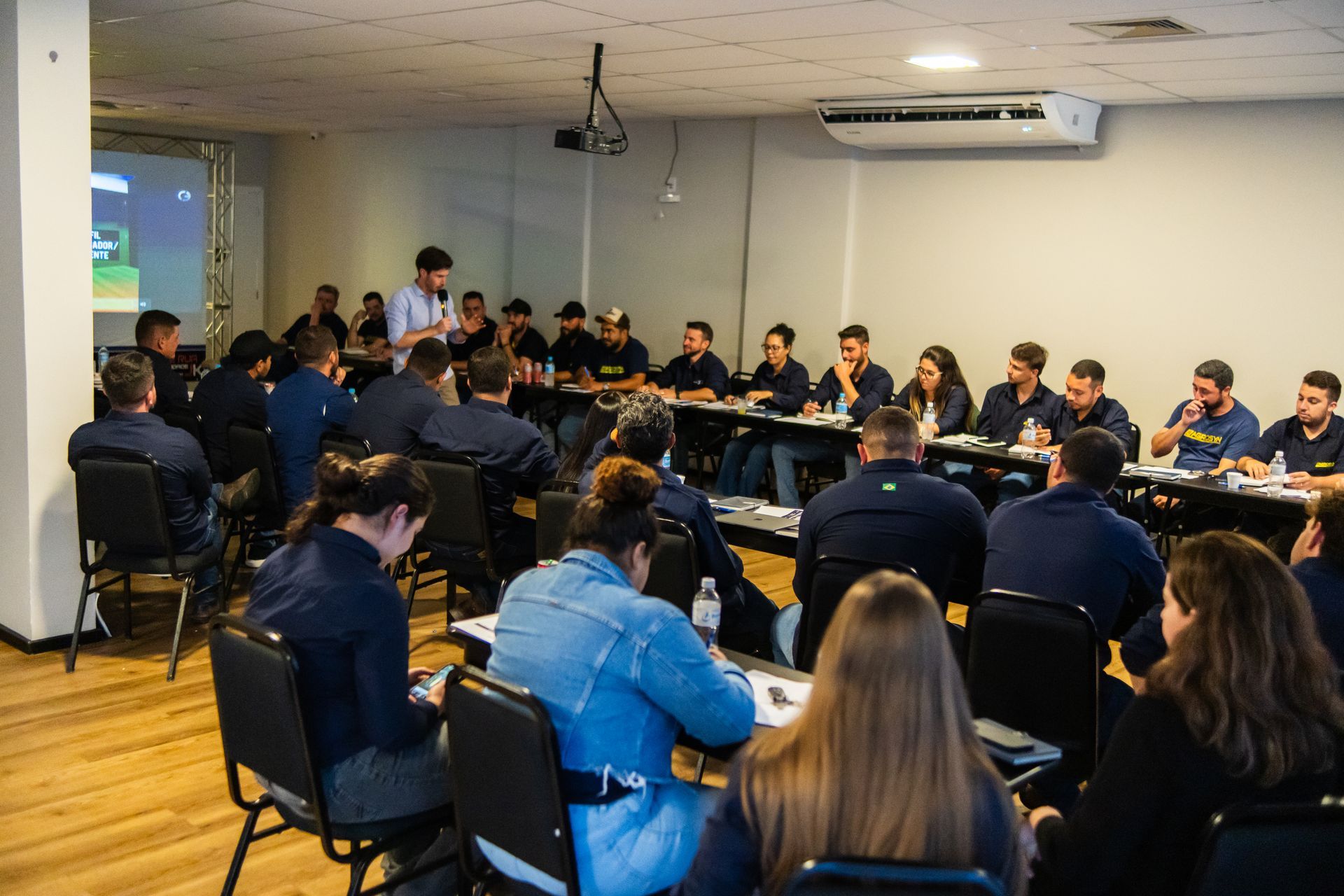 Uma grande sala de conferências com mesas e cadeiras preparadas para uma reunião.