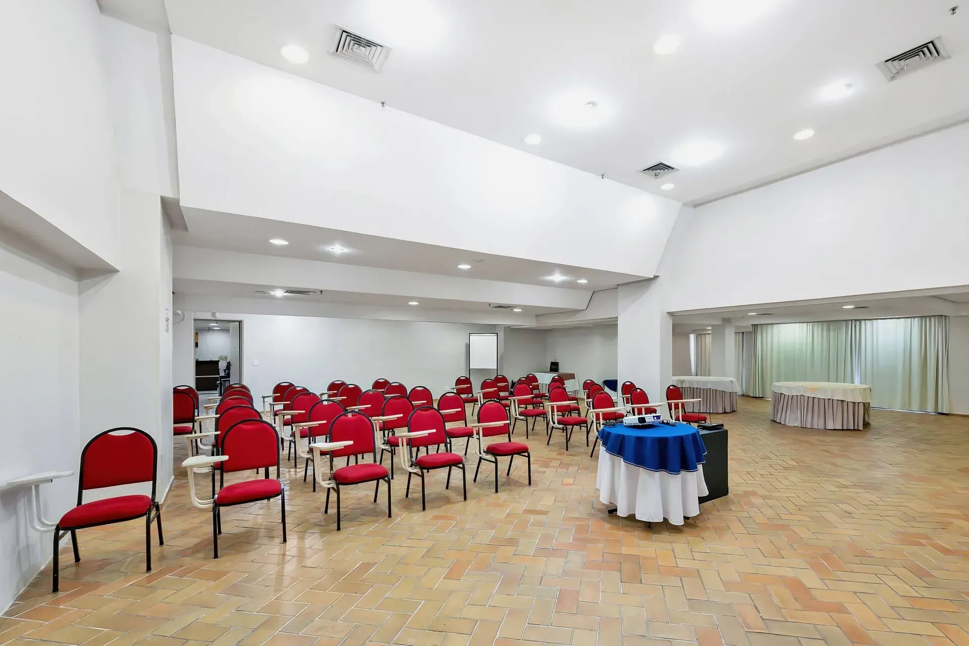 Uma grande sala de conferências com mesas e cadeiras preparadas para uma reunião.