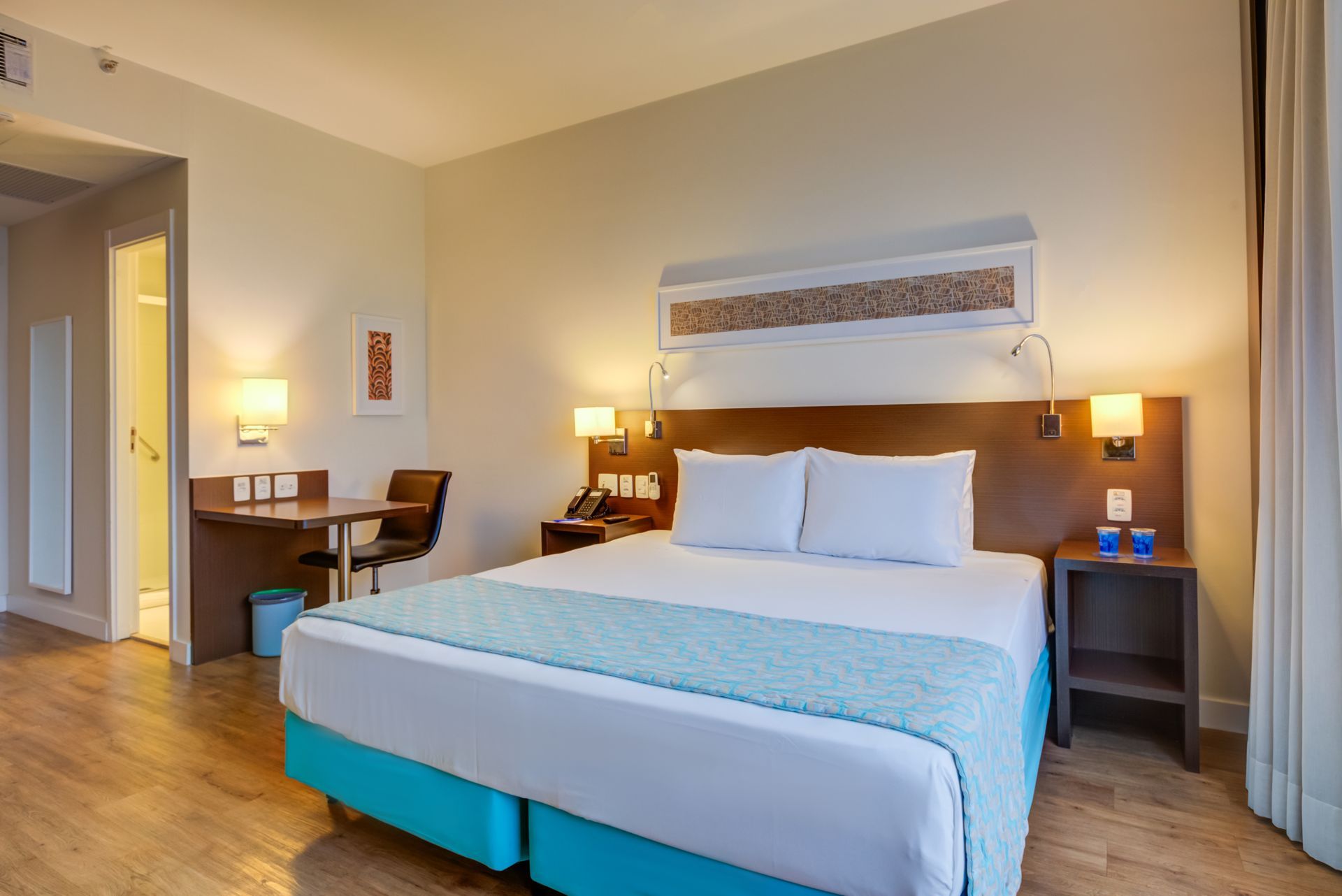 Um lobby de hotel com paredes roxas, um balcão de recepção, cadeiras e um tapete redondo.