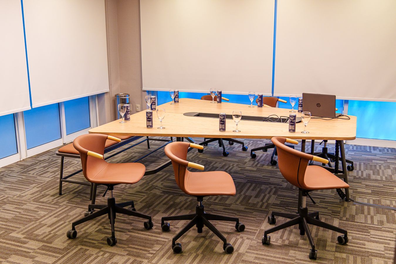 Uma sala de conferências com uma mesa, cadeiras e um laptop.