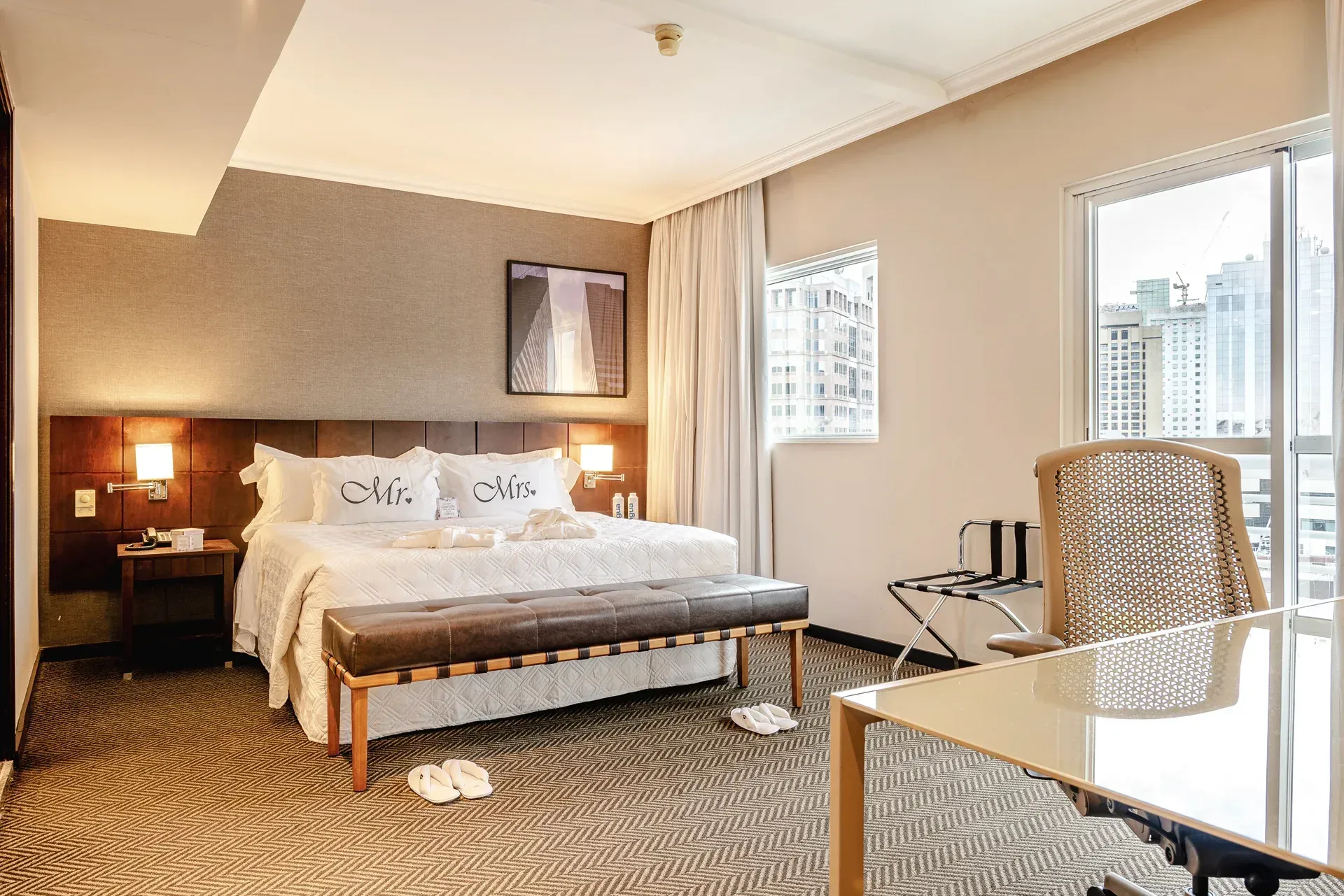 Um quarto de hotel com uma cama king size e uma cadeira de balanço.
