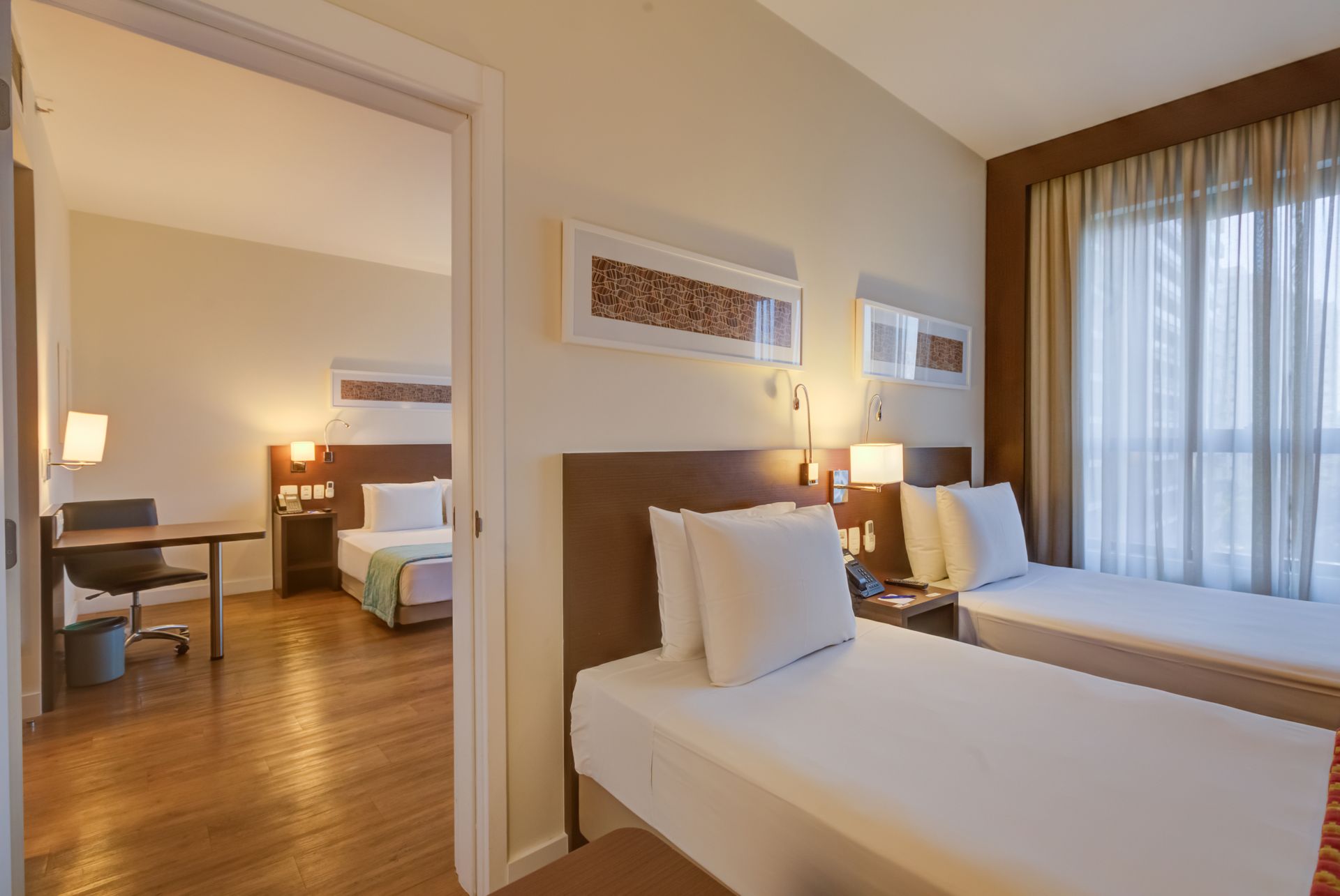 Um quarto de hotel com uma cama king size e uma escrivaninha.