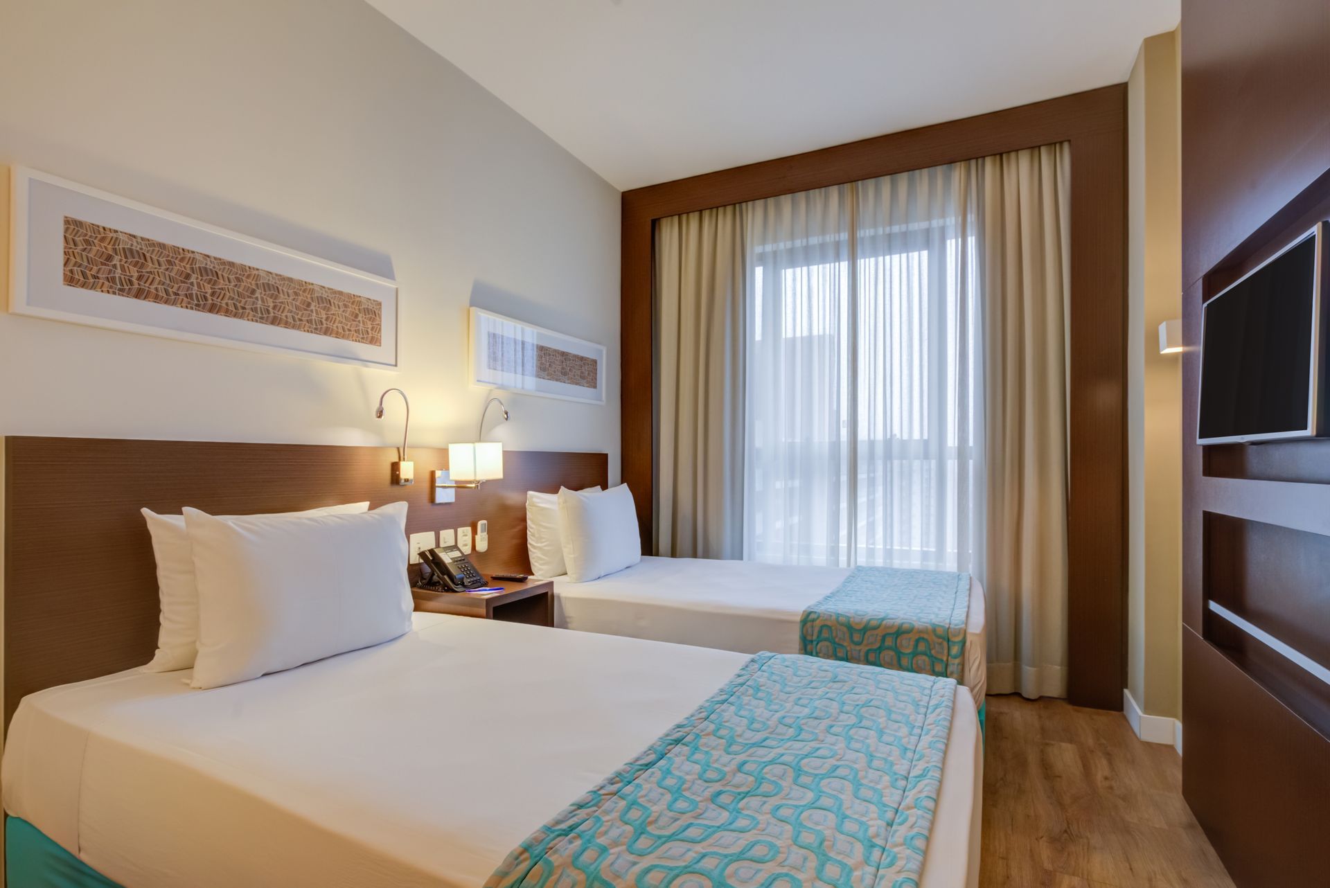 Um quarto de hotel com uma cama, cadeira, escrivaninha e espelho.