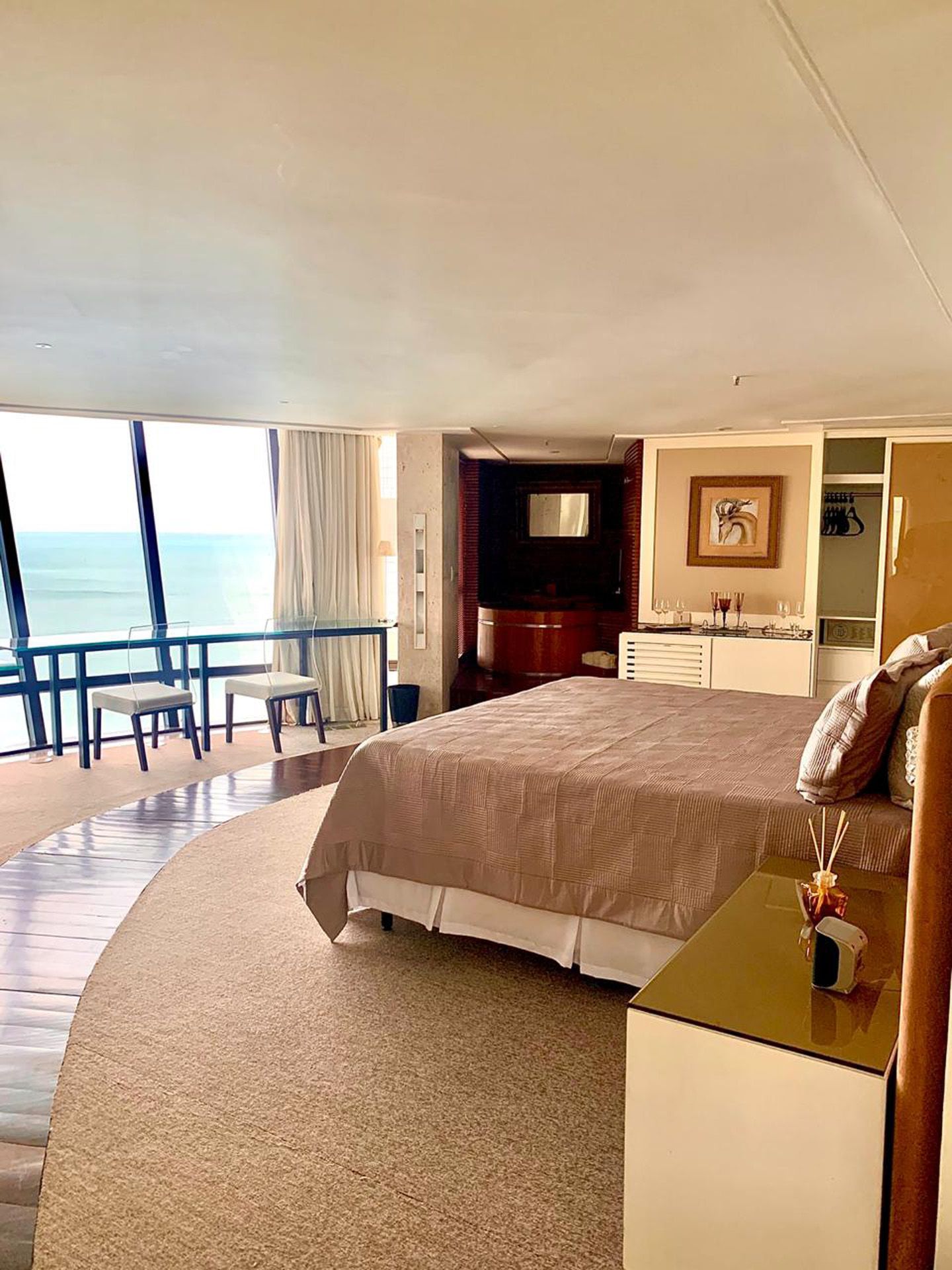 Há uma cama grande no meio do quarto com vista para o oceano.
