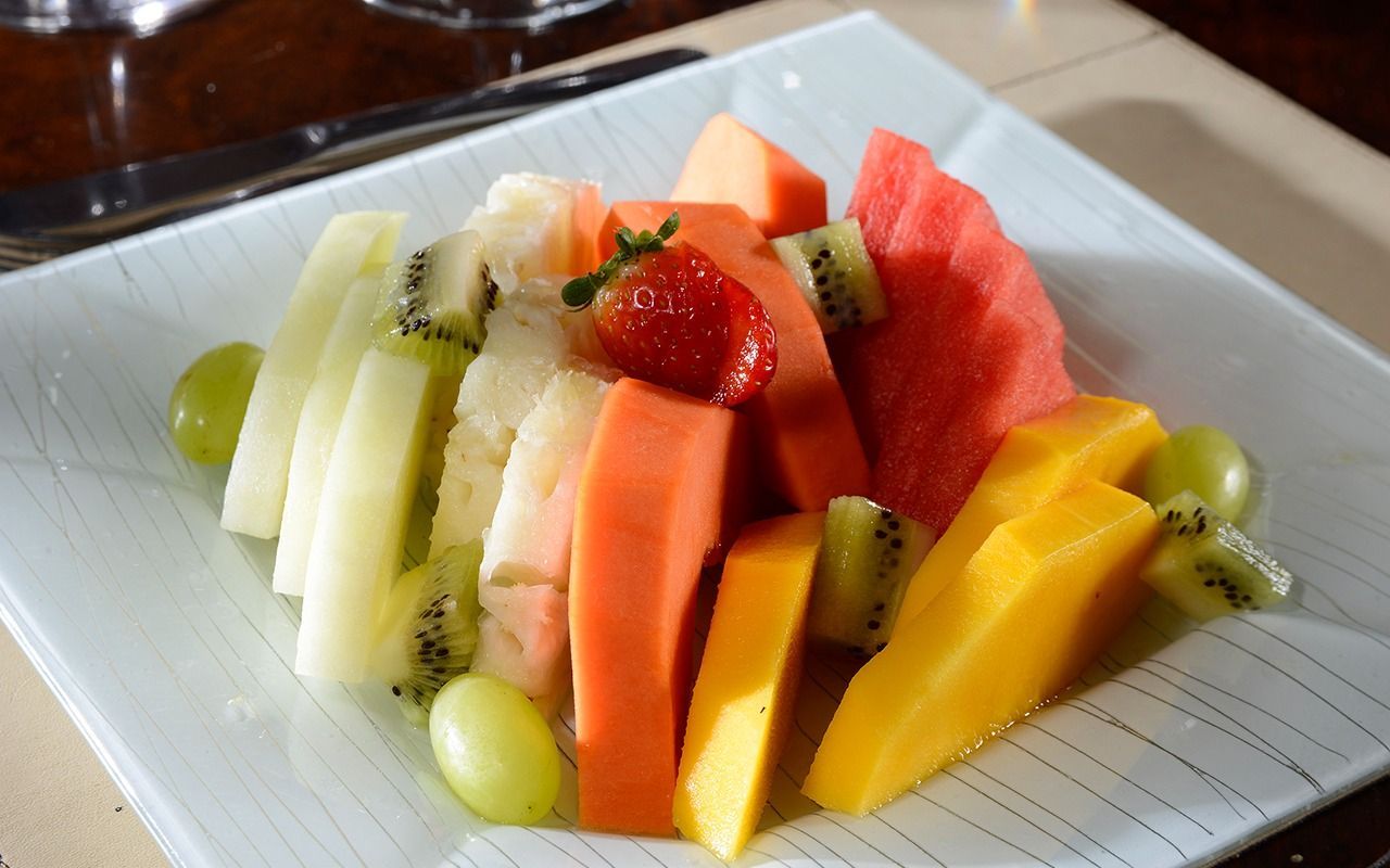 Um prato branco coberto com frutas fatiadas sobre uma mesa