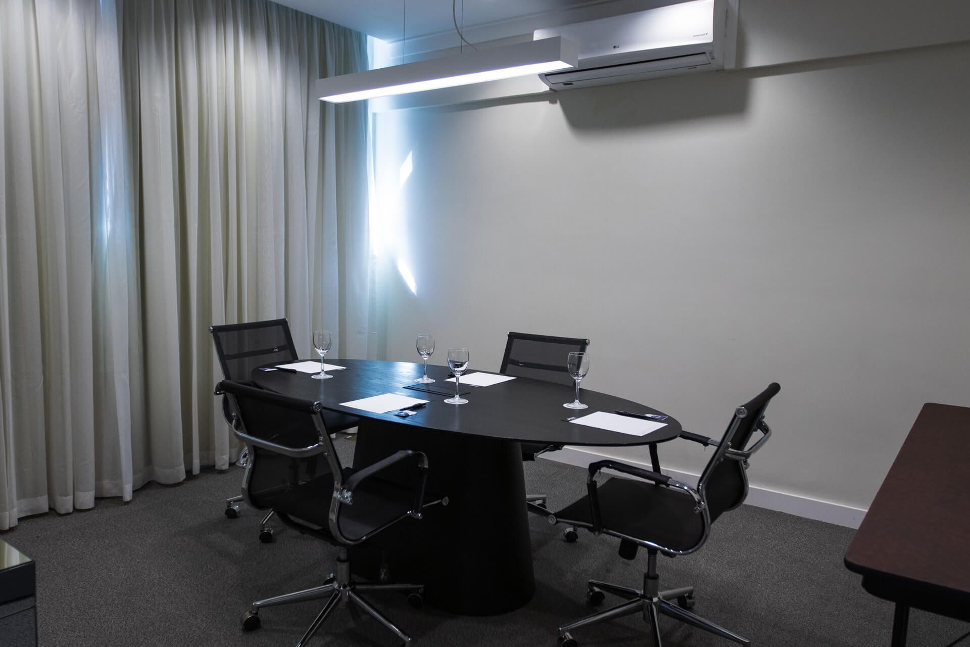 Uma sala de conferências com uma mesa redonda e cadeiras.