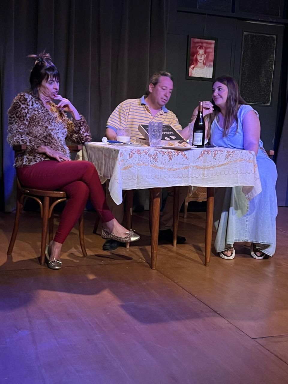 Un grupo de personas está sentada en una mesa con una botella de vino.