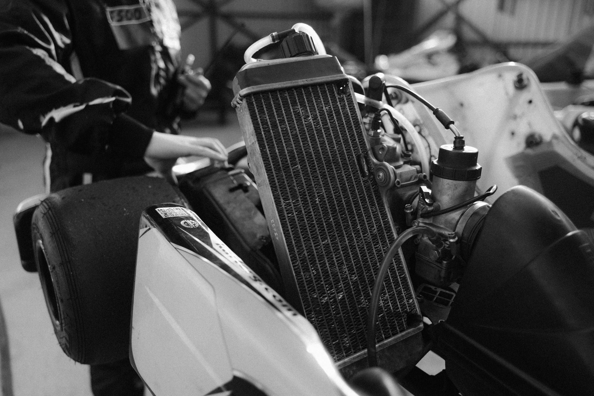 Go-kart engine, radiator, and tires; mechanic working on the vehicle.