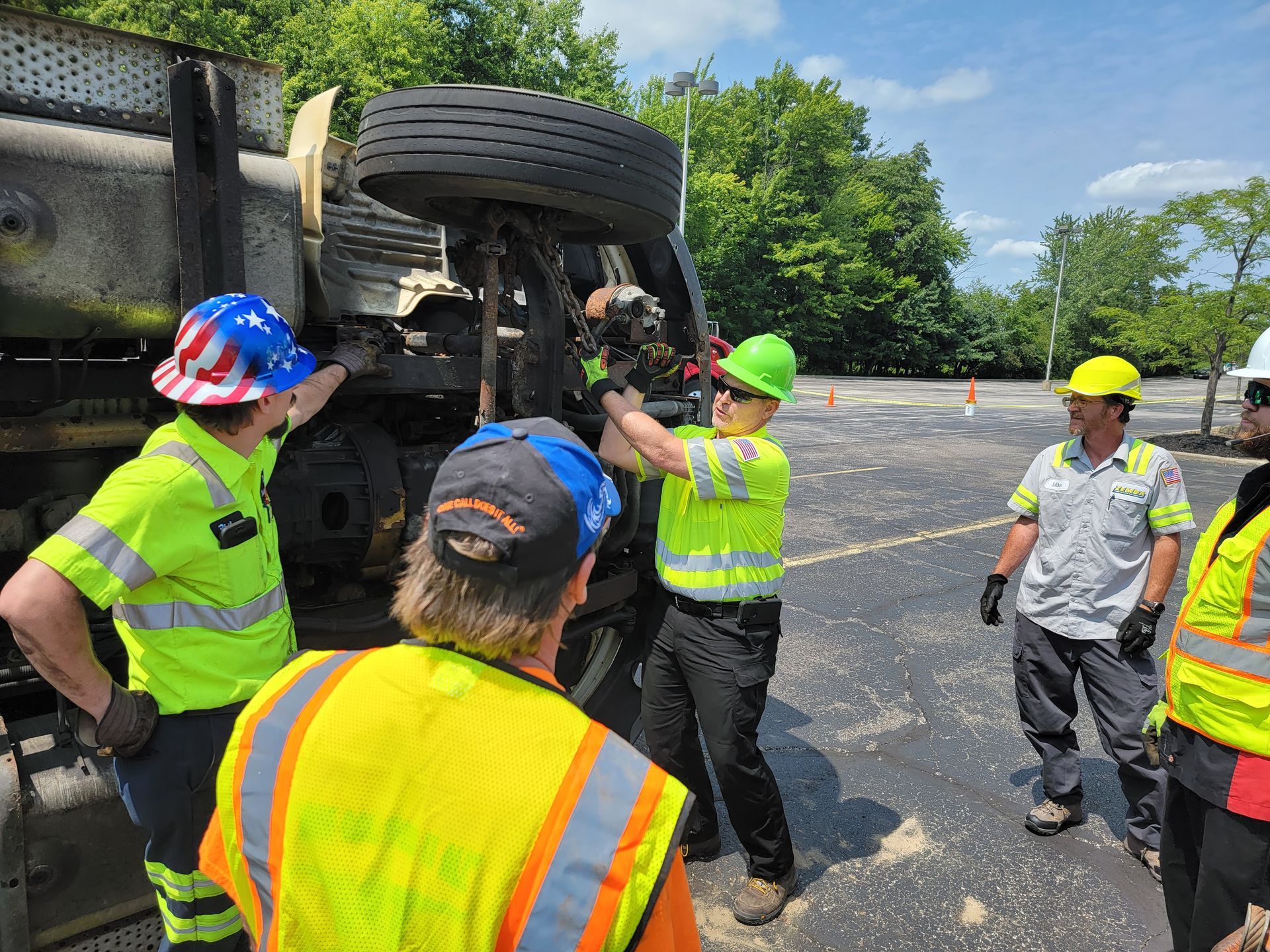 Workers in neon safety vests inspect an overturned truck on a road