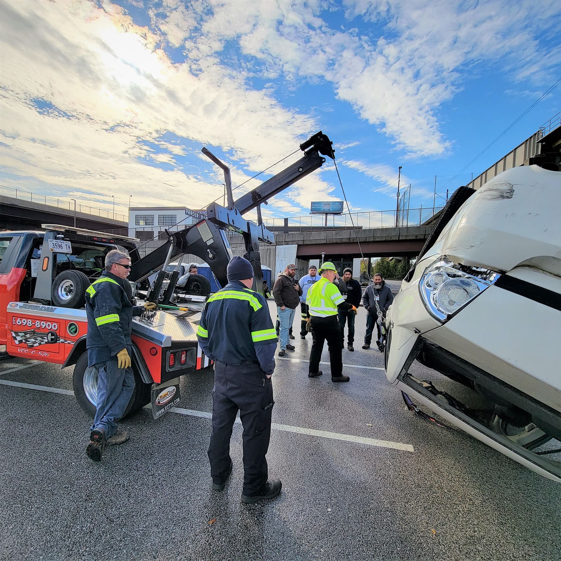 Emergency responders at a highway crash beside an overturned white truck and damaged vehicle parts