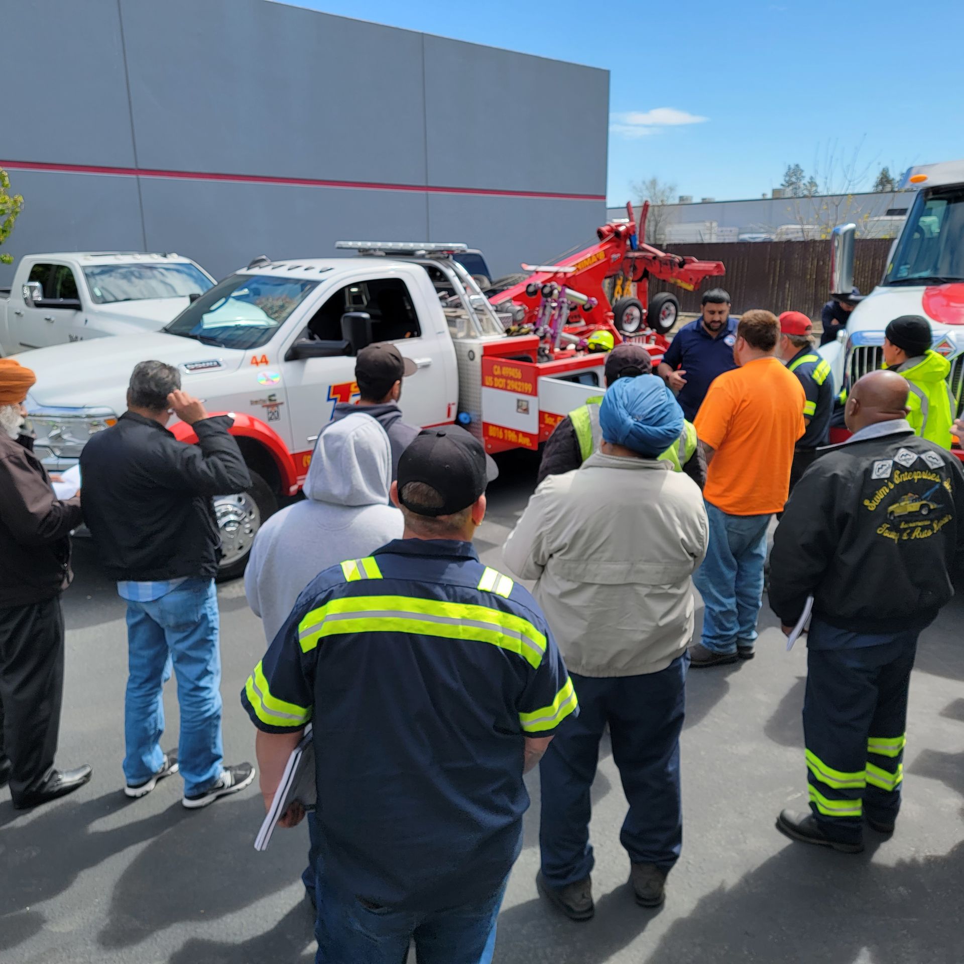Crowd watches tow truck loading a white van in a parking lot