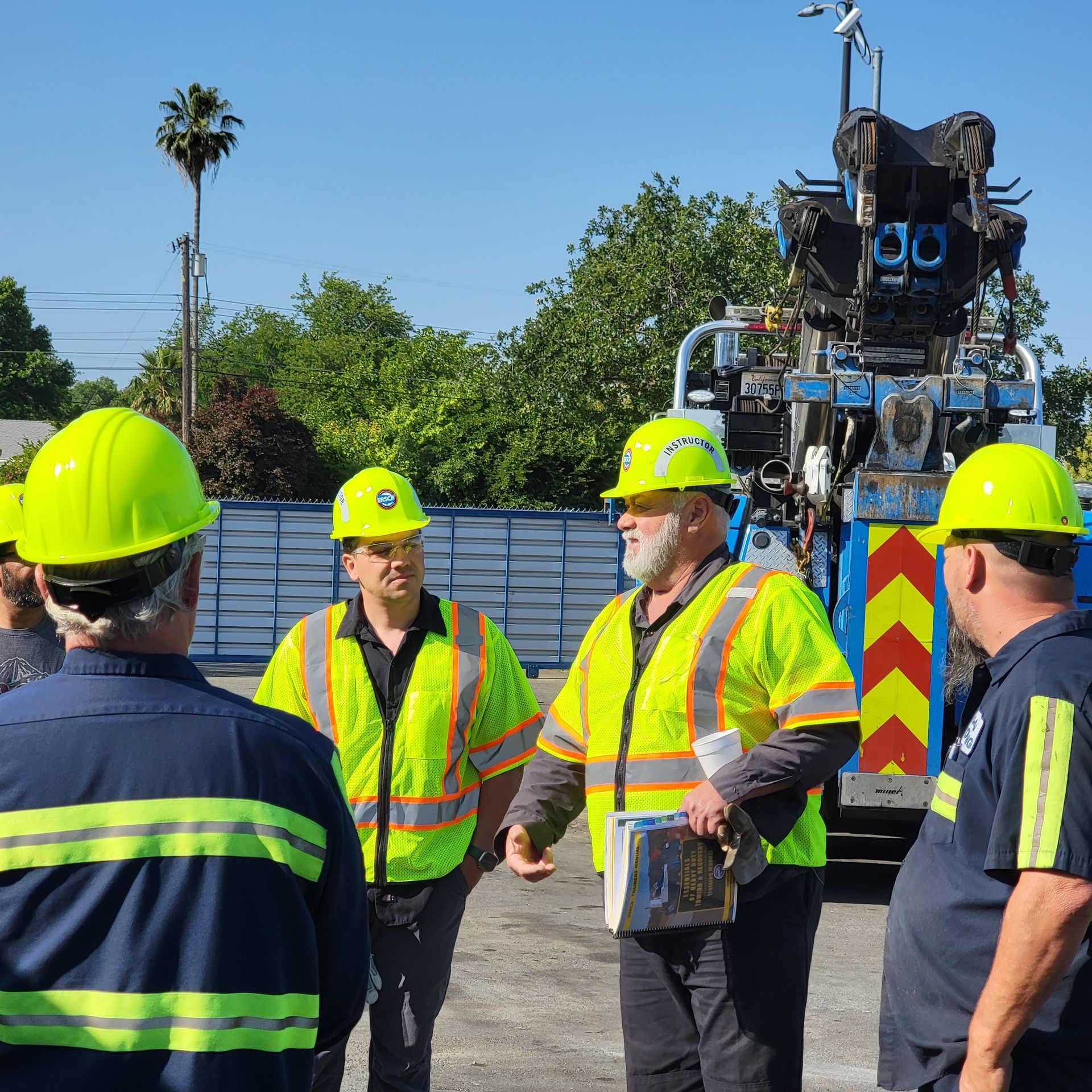 Utility workers in neon safety vests and hard hats talking beside a service truck outdoors