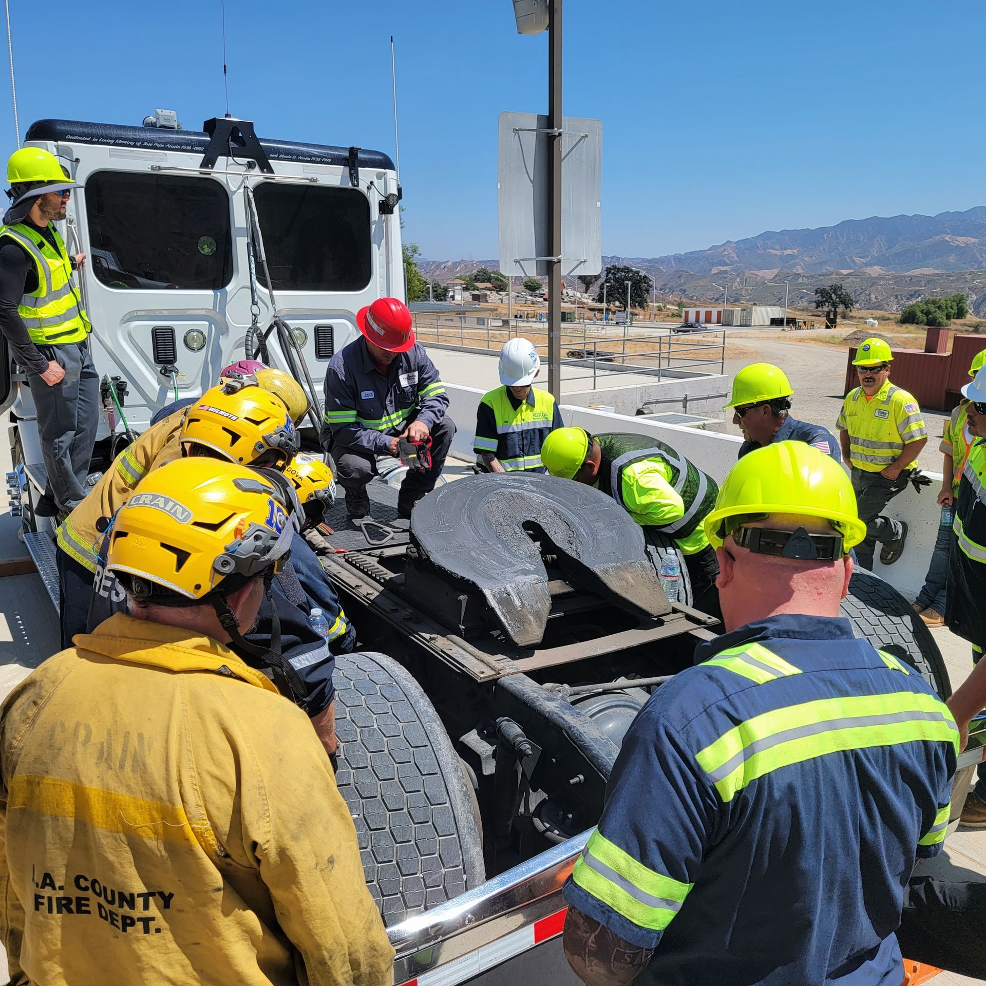 Firefighters in yellow helmets rescuing a person from a crushed car beside a highway