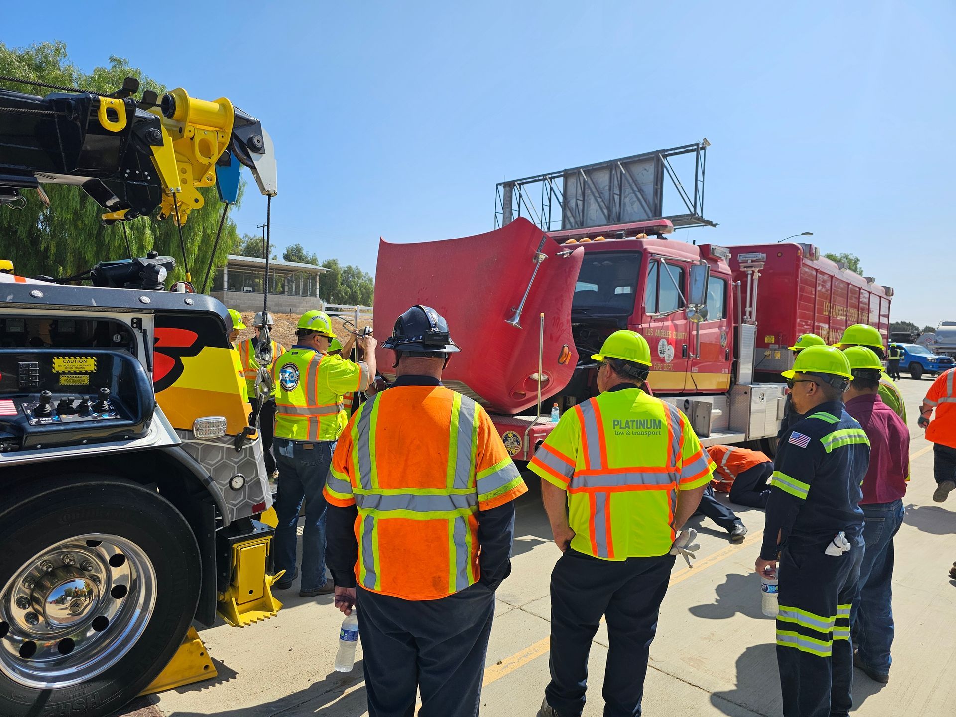 Firefighters and workers gather beside a red truck on a highway under a clear sky