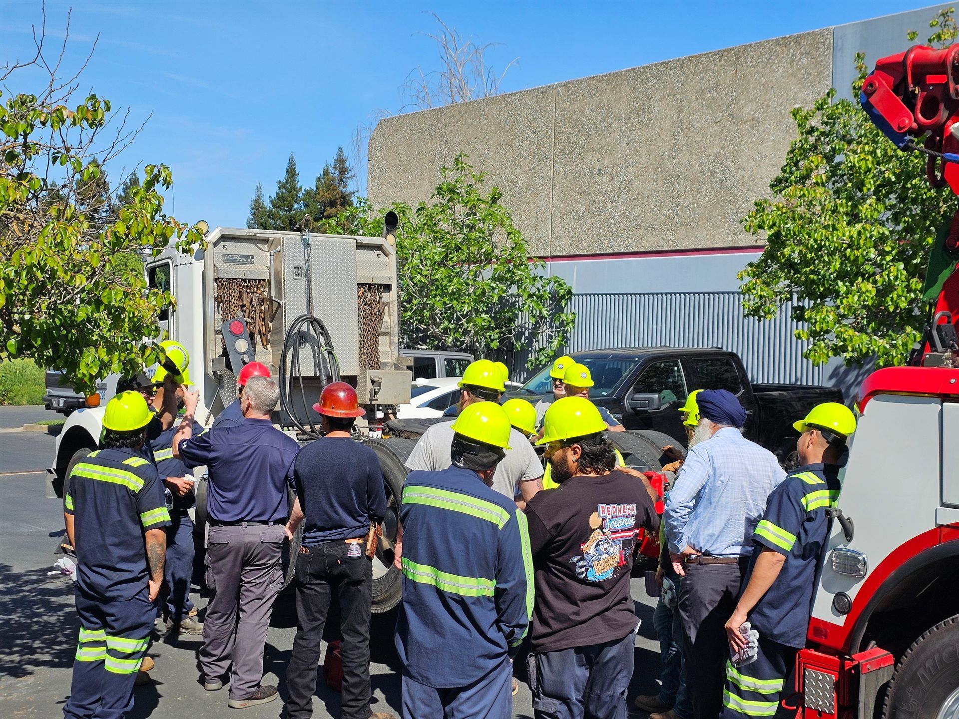 Emergency responders in helmets gather around a fire truck at an outdoor scene.