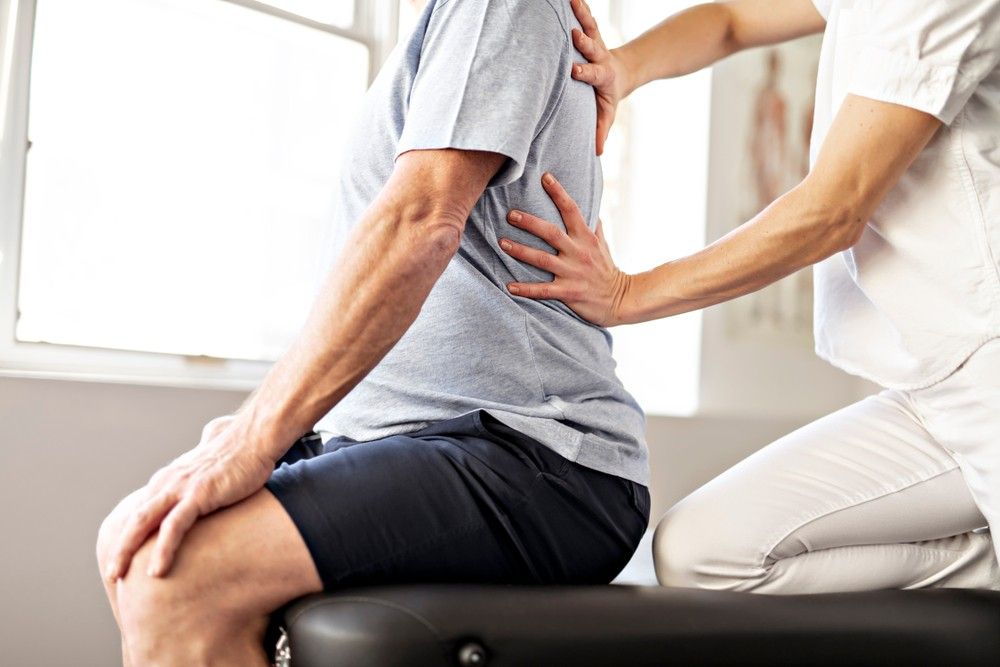A Man is Sitting on a Table Getting a Massage From a Nurse — Mark O'Brien Chiropractic in West End, QLD