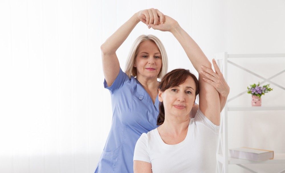 A Nurse is Helping a Woman Stretch Her Arms — Mark O'Brien Chiropractic in West End, QLD