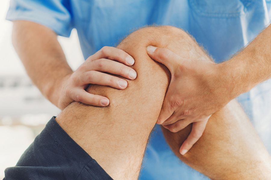 A Man is Getting His Knee Examined by a Doctor — Mark O'Brien Chiropractic in West End, QLD