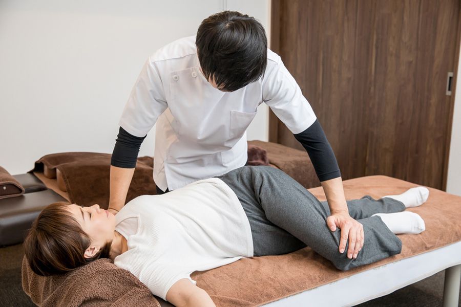 A Man is Giving a Woman a Massage on a Bed — Mark O'Brien Chiropractic in West End, QLD
