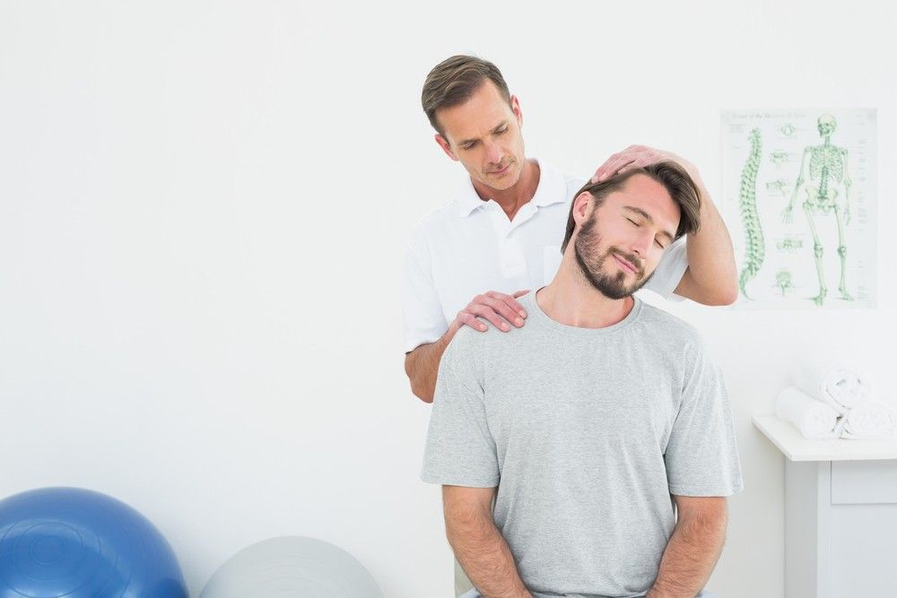 A Man is Getting His Neck Examined by a Doctor — Mark O'Brien Chiropractic in West End, QLD